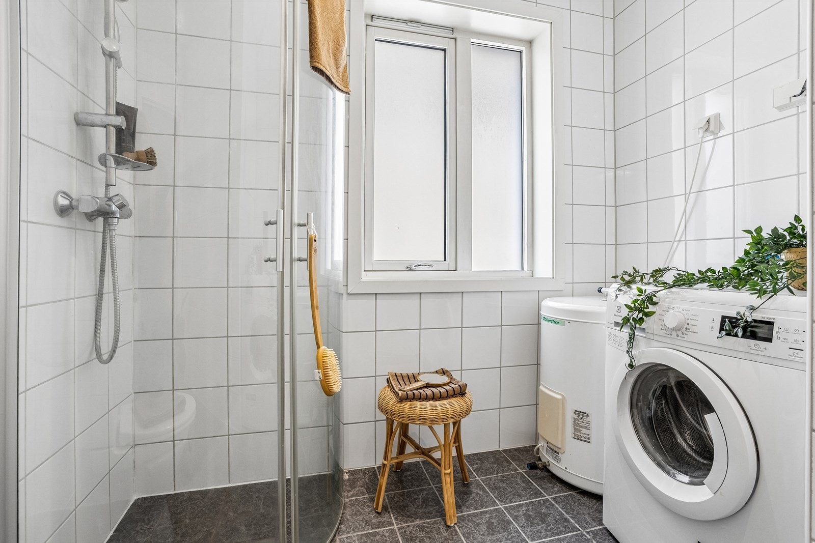 Badet har dusjhjørne, toalett og opplegg for vaskemaskin. Galleribilde