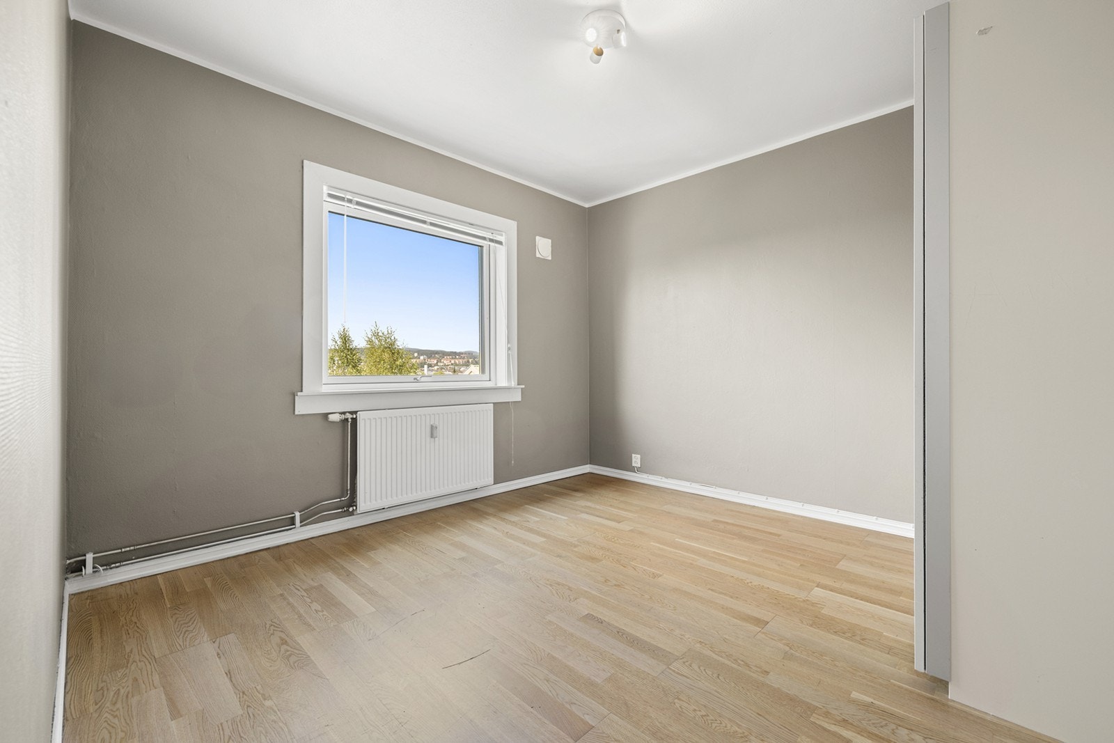 Rommet har gulv av parkett og vegger med tapet, og det er innfelte strømkontakter. Galleribilde