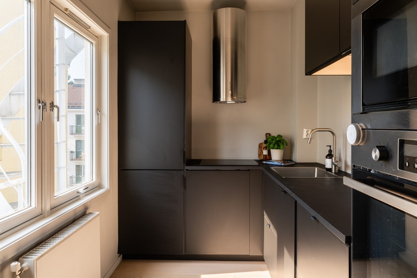 Separat kjøkken med stilren IKEA-innredning fra 2020 med sorte, glatte fronter og grå/sorte laminatbenkeplate. Galleribilde