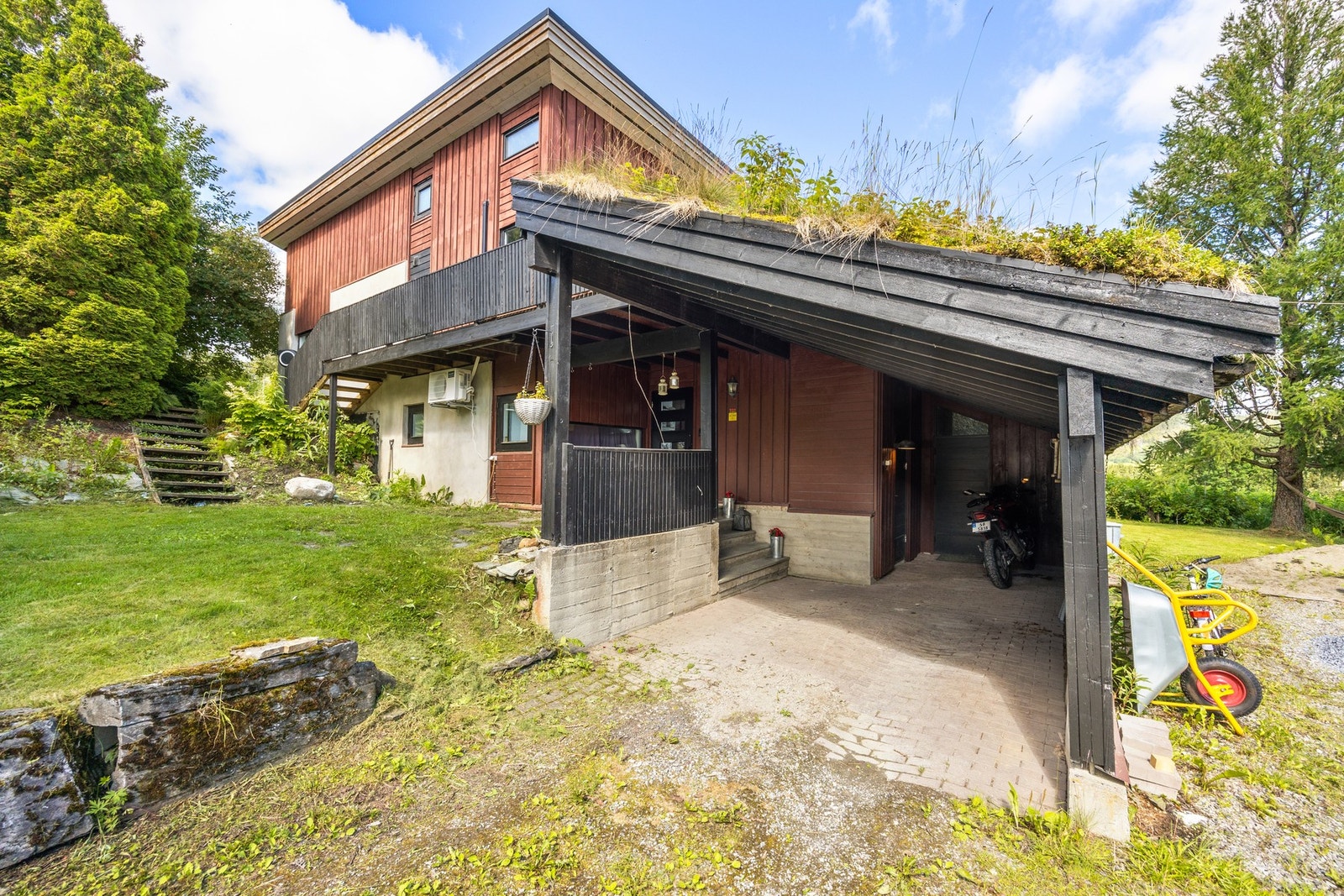 Carport i tilknytning til inngangsparti. To boder i bakkant av carport, der den til venstre er isolert. Galleribilde