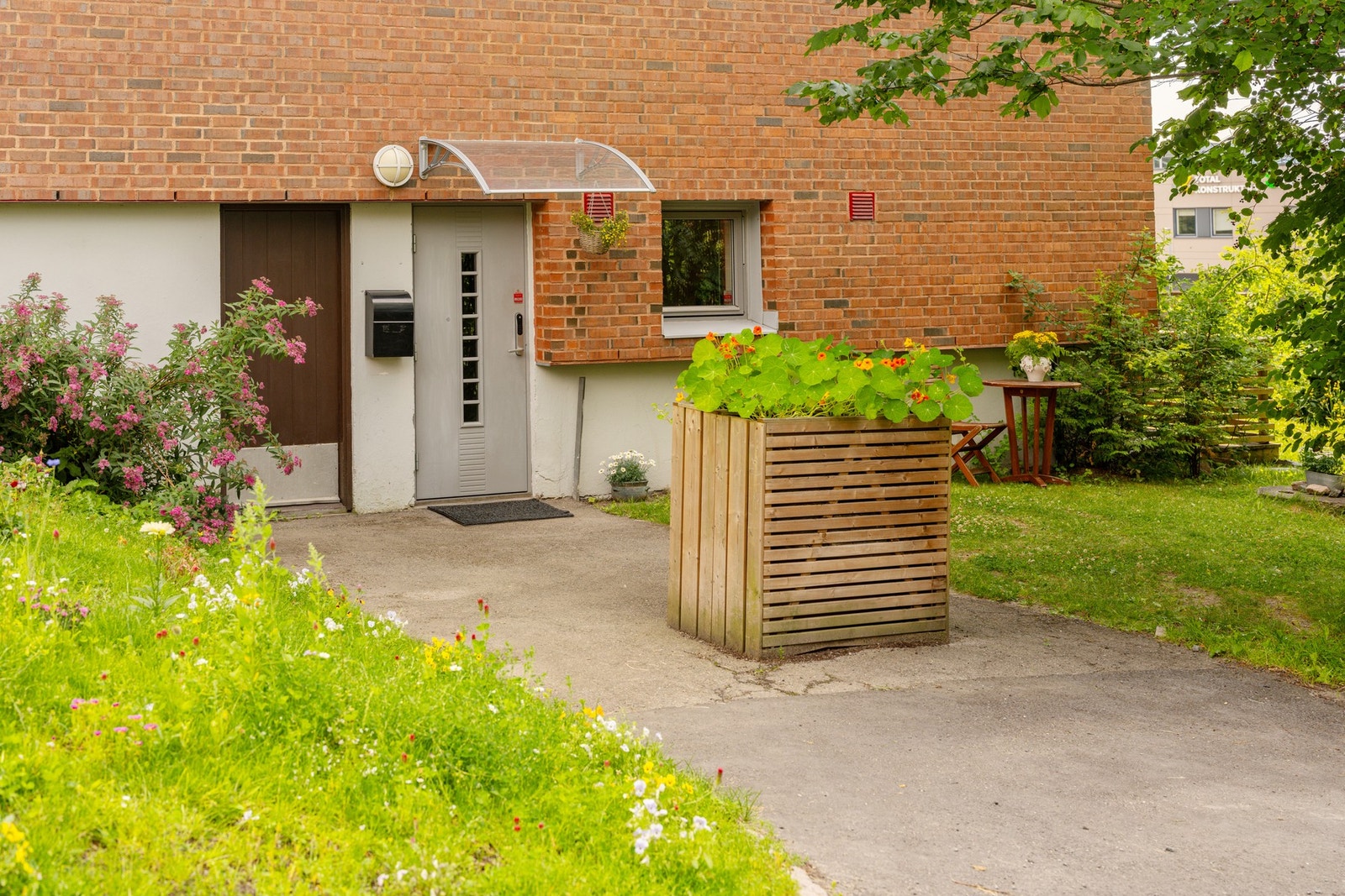 Koselig frodig inngangsparti med blomsterkasse og andre beplantninger. Galleribilde