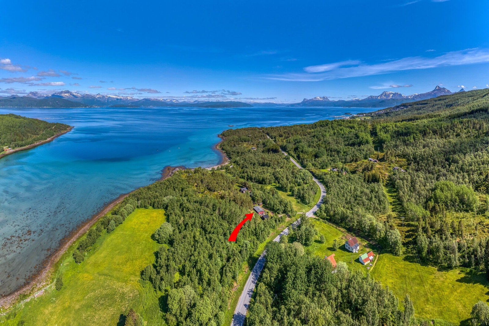 Eiendommen er markert med pil, med fjorden og fjellene i bakgrunnen. Galleribilde