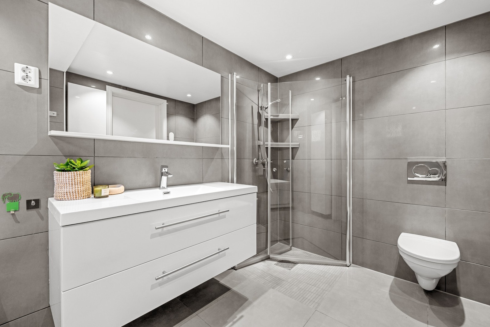 Badet har varmekabler i gulv, og er innredet med dusjhjørne, badekar, vegghengt WC og moderne innredning. Galleribilde