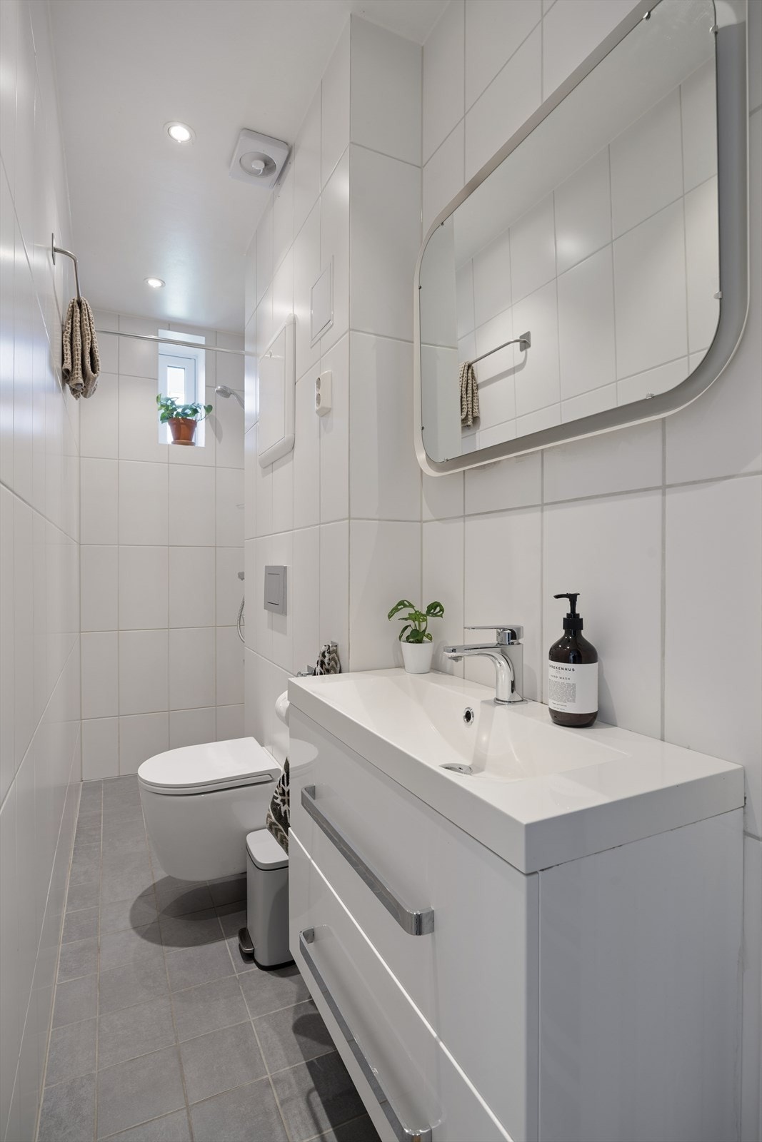 Badet har en arealeffektiv utforming hvor hver kvadratmeter er godt utnyttet. De lyse flisene og innfelte downlights skaper et rent og moderne preg. Galleribilde