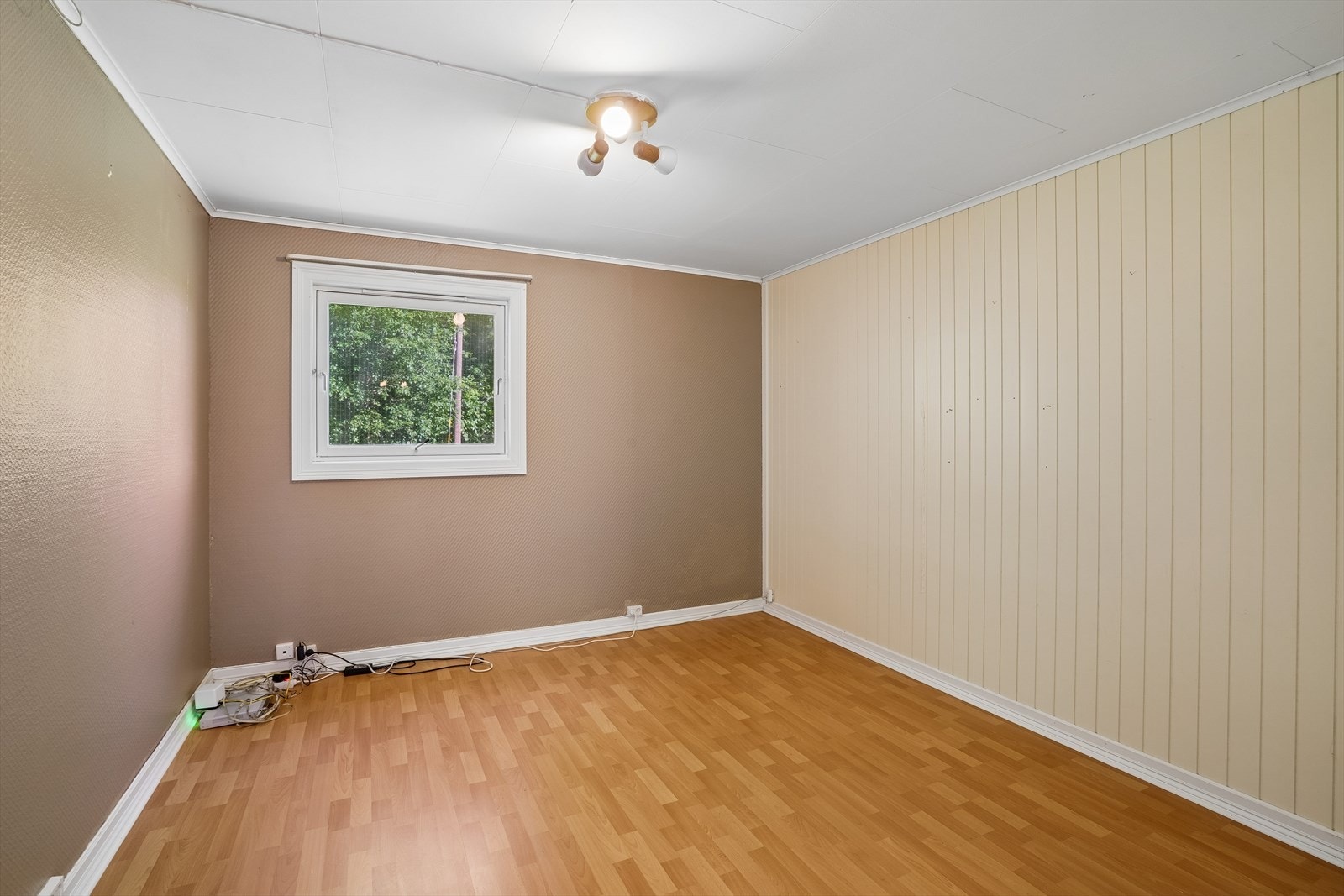 Soverom med laminat på gulv og vegger med tapet og panel. Galleribilde