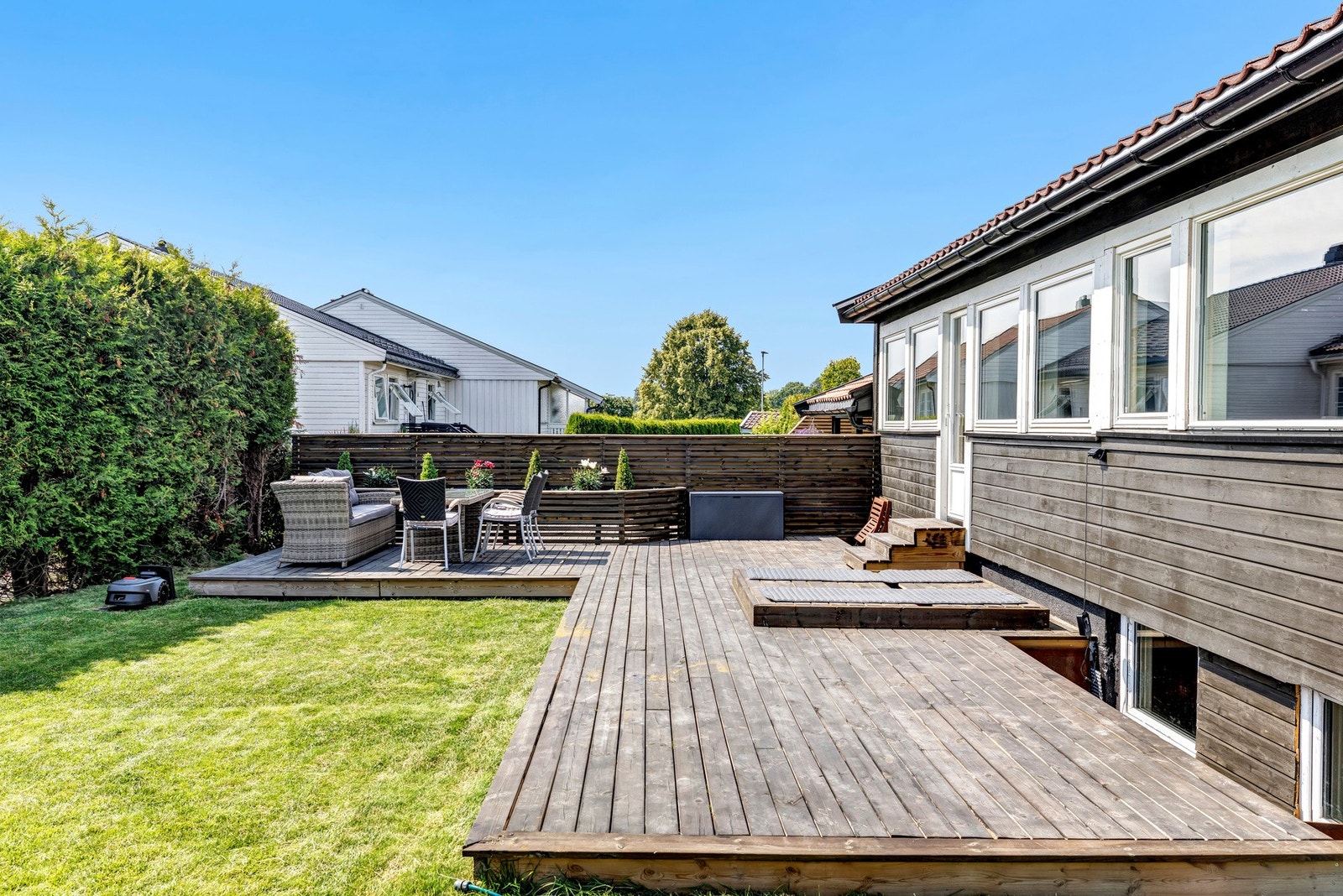 Stor og solrik terrasse med direkte adkomst til hagen - et flott uterom for både lek og hyggelige stunder med familie og venner. Galleribilde