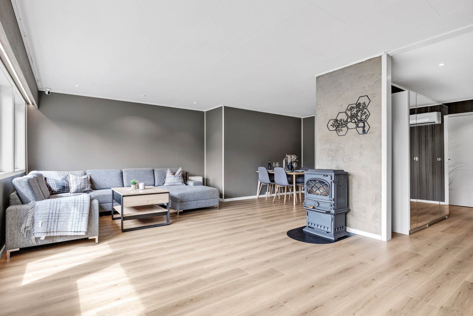 Boligen har en åpen stue- og kjøkkenløsning som skaper en sosial og funksjonell planløsning. Her er det god plass til både sofagruppe og spisebord, samtidig som de store vinduene gir rikelig med dagslys. Galleribilde