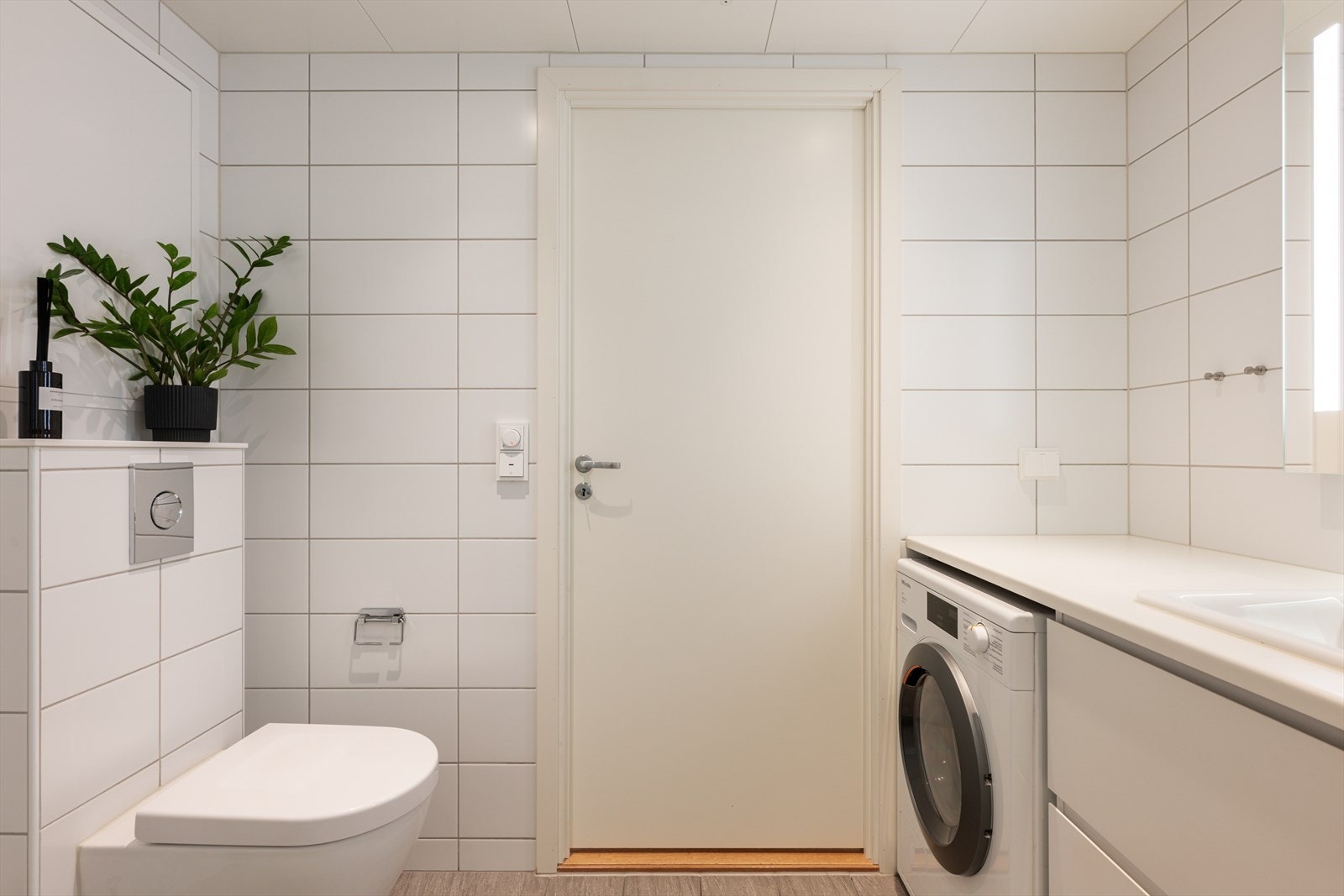 Badet har vegghengt toalett og opplegg for vaskemaskin. Galleribilde