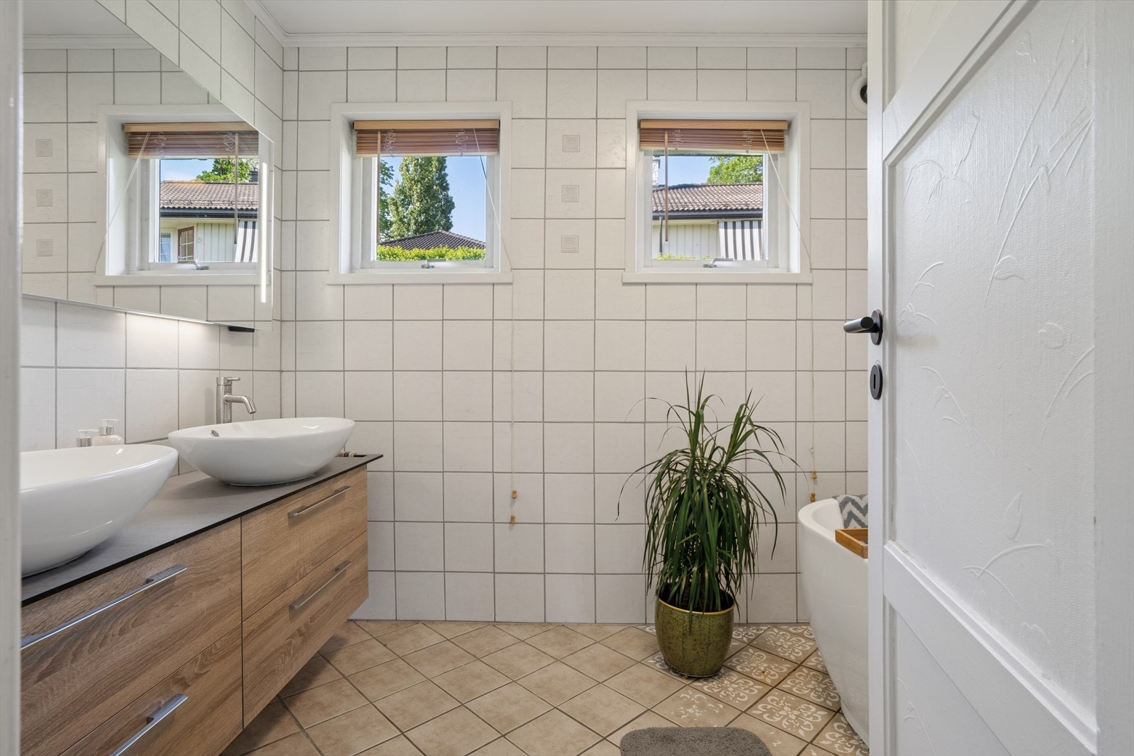Badet i hovedetasjen har flislagt gulv med varmekabler og innredning med dobbel servant, montert i 2019. Galleribilde