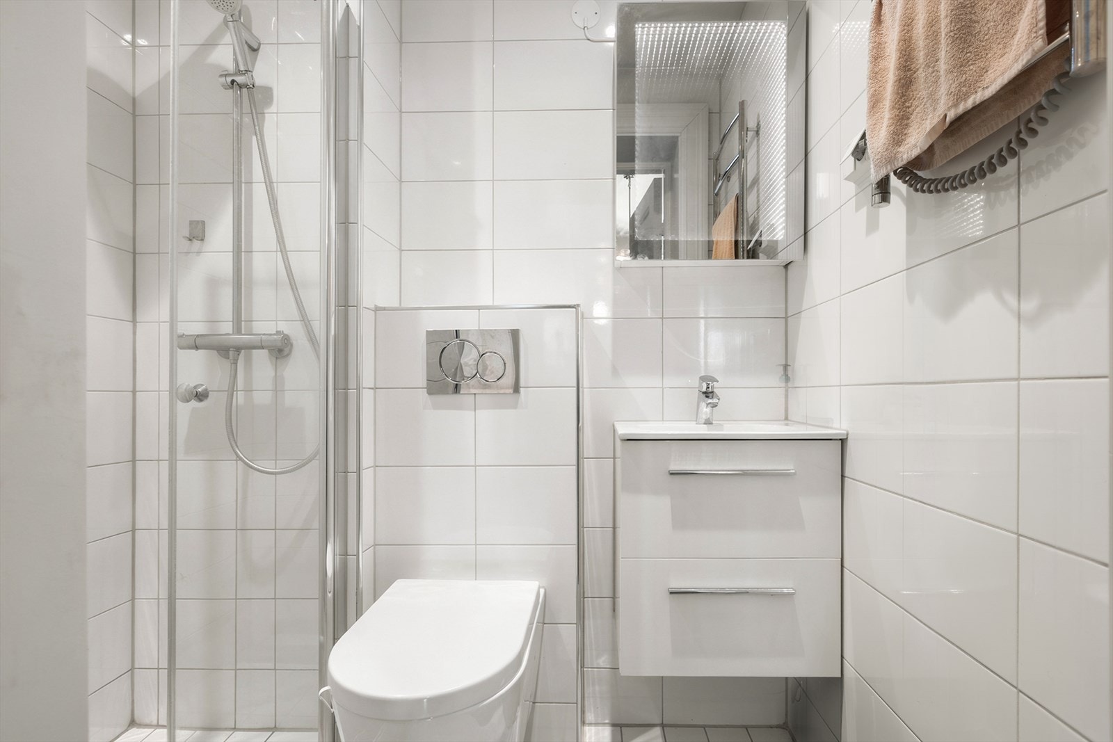 Badet har dusjhjørne, vegghengt toalett og mekanisk avtrekk. Galleribilde