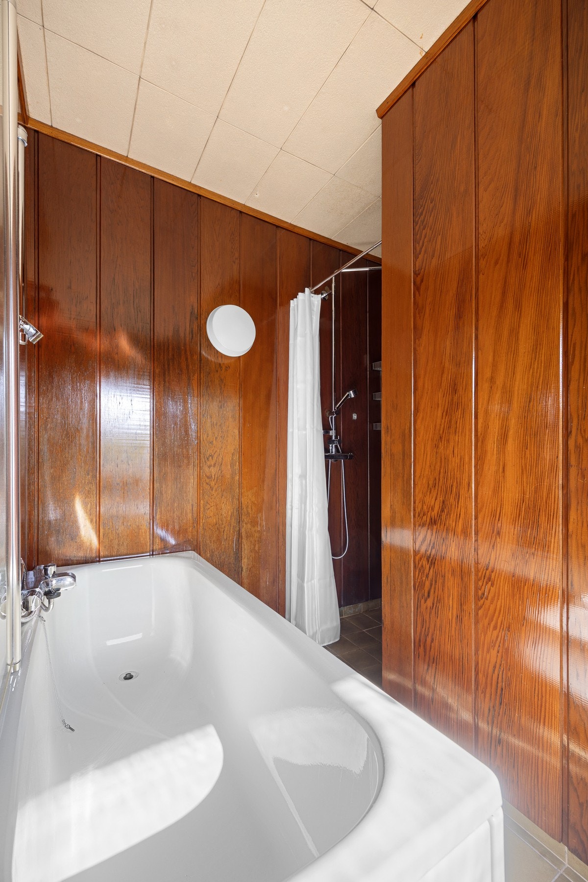 Rommet har flislagt gulv med elektriske varmekabler, mens veggene er utført med redwood panel og synlig tømmer som gir badet et særpreget og lunt uttrykk. Galleribilde
