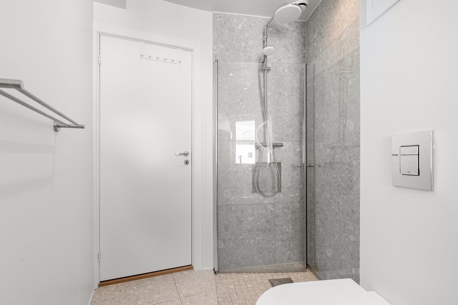 Badet inneholder dusjhjørne, baderomsinnredning med nisje til vaskemaskin og toalett. Galleribilde