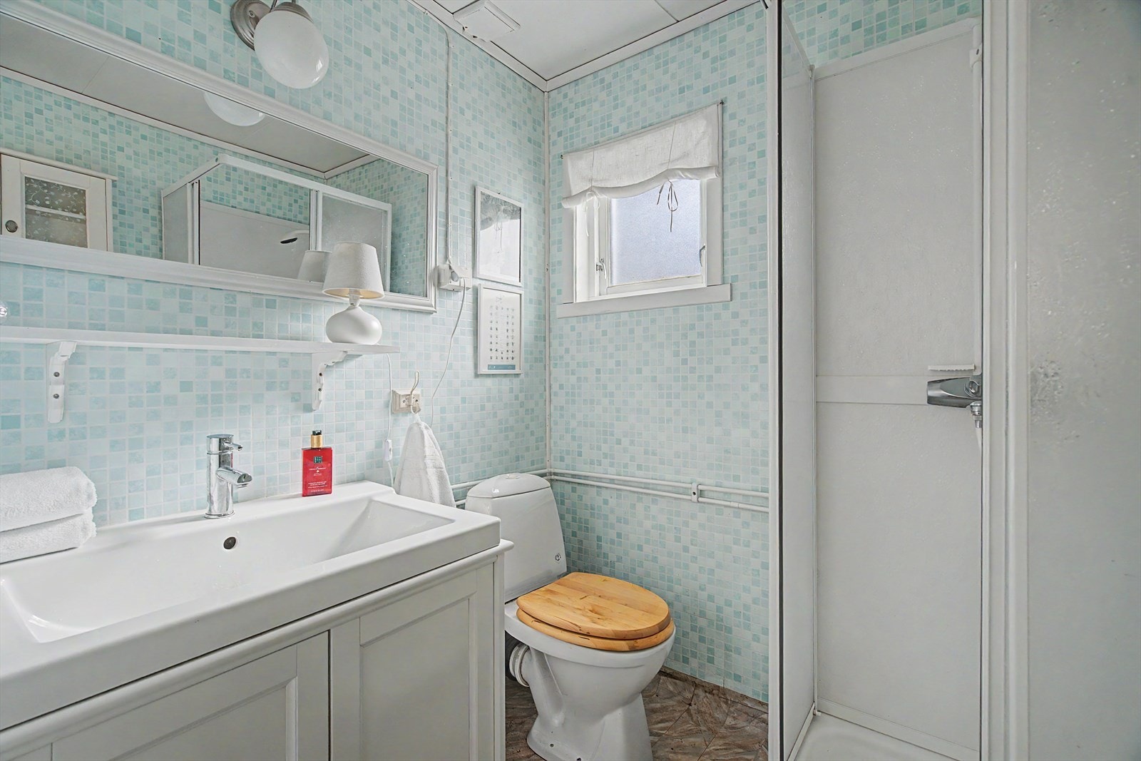 Badet ble tilbygget rundt 1990 og har vinylbelegg på gulv, våtromstapet på veggene og dusjkabinett. Galleribilde