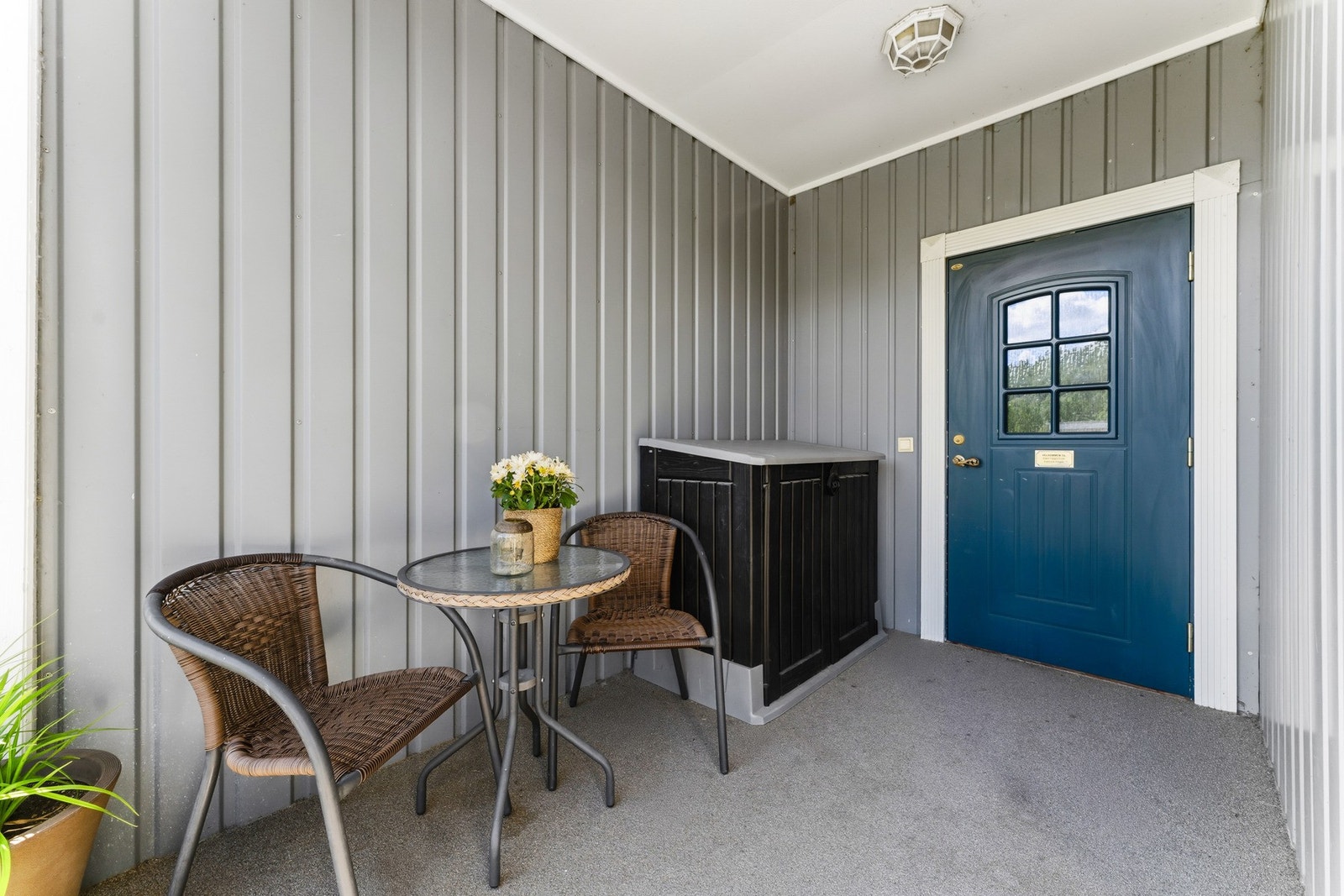 Overbygd inngangsparti med plass til en liten sittegruppe. Galleribilde