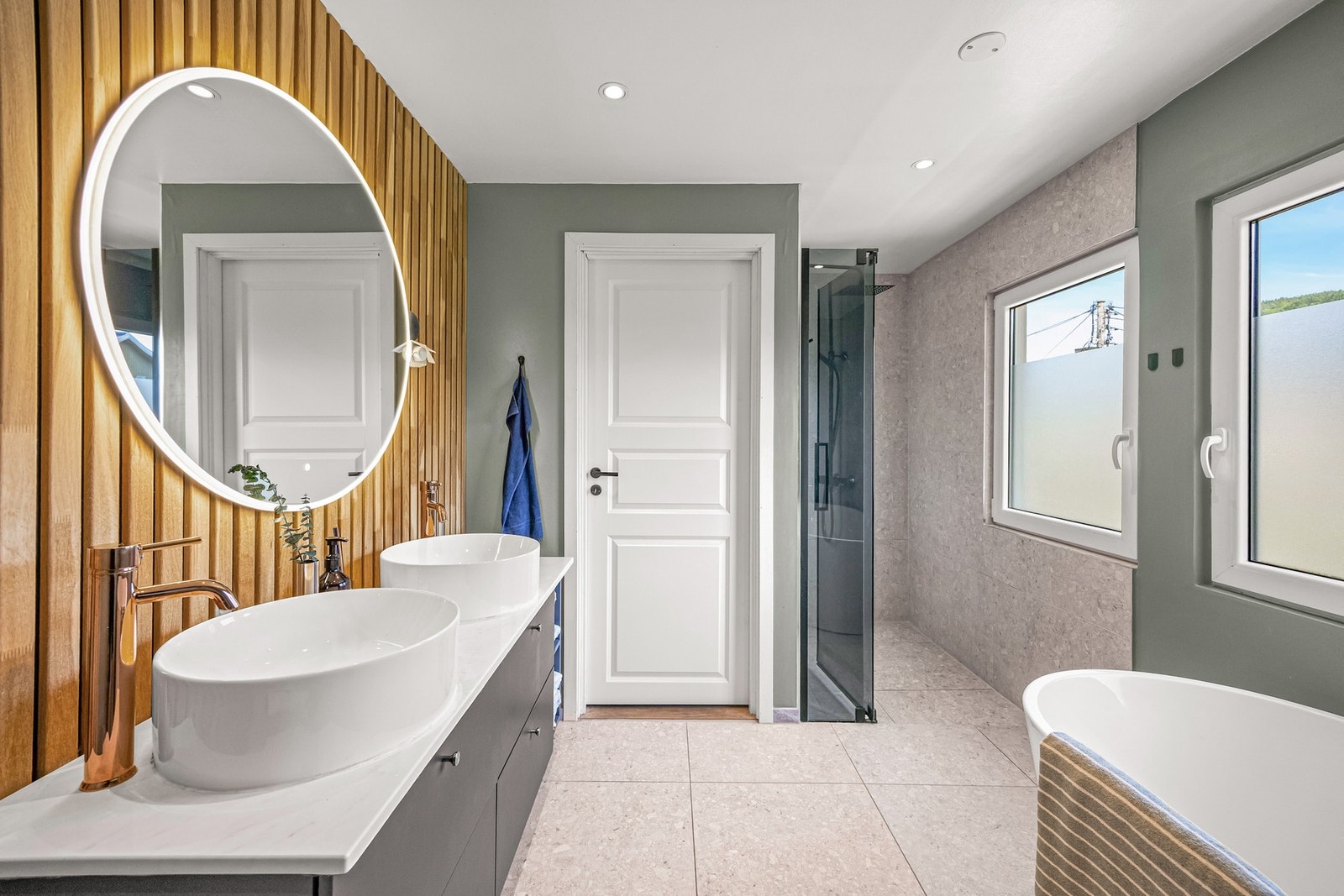 Stor innredning med dobbel vask, design badekar med dusjutstyr, varmekabler og downlights i himling Galleribilde