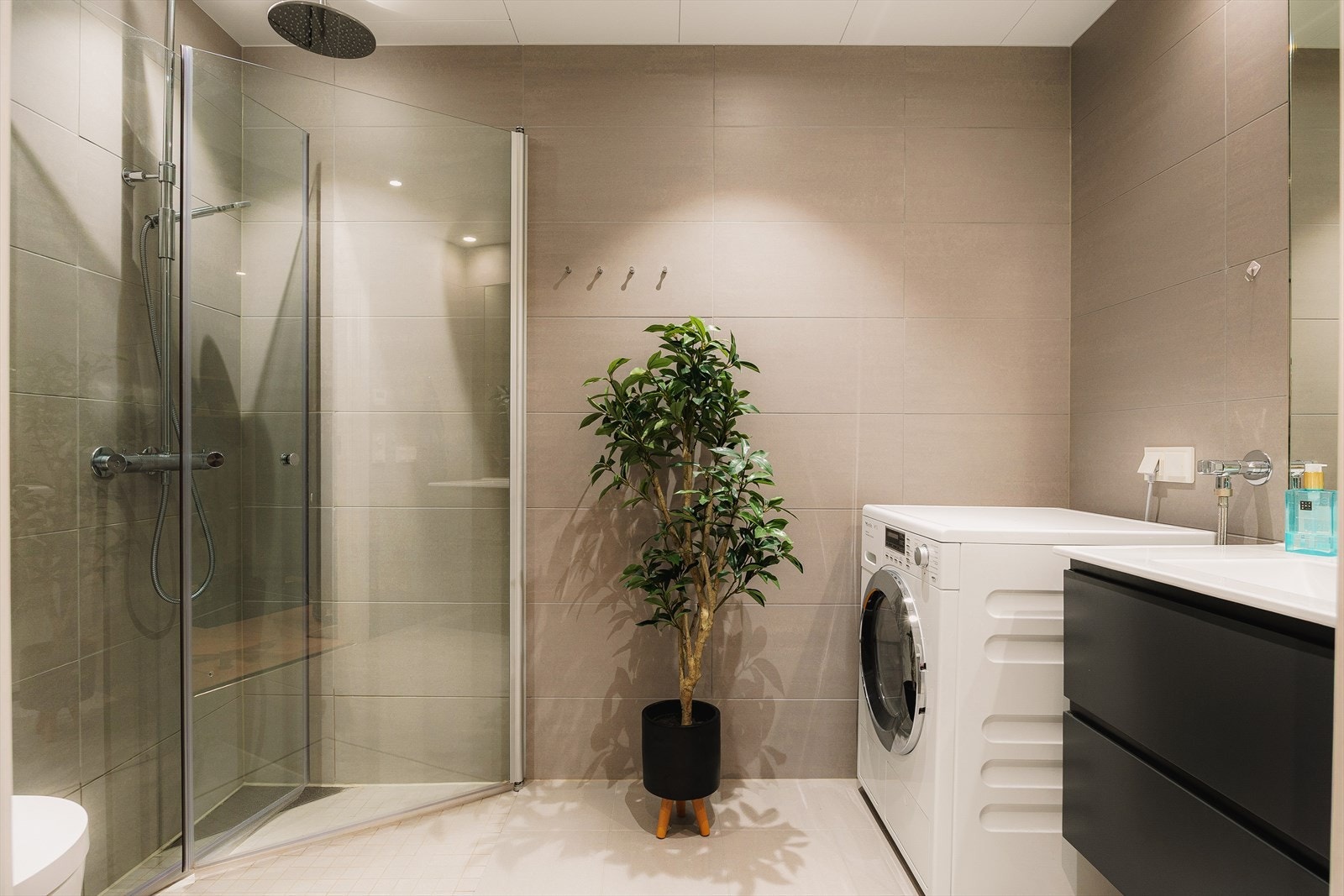 Badet har en moderne utførelse med gulvvarme, dusjhjørne og opplegg for vaskemaskin. Galleribilde
