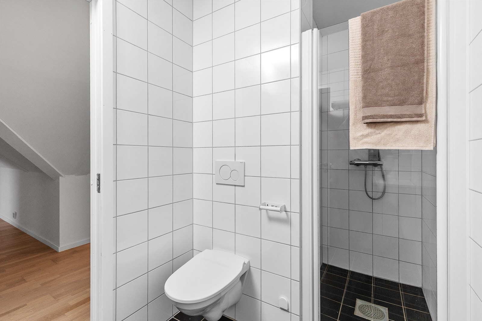Badet er innredet med dusjdør av glass, vegghengt do, innredning med servant og opplegg for vaskemaskin. Galleribilde