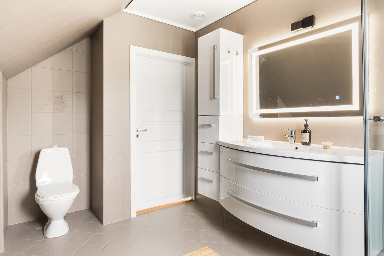 Badet i loftsetasjen har er helfliset med dusjkabinett, baderomsinnredning og toalett. Galleribilde
