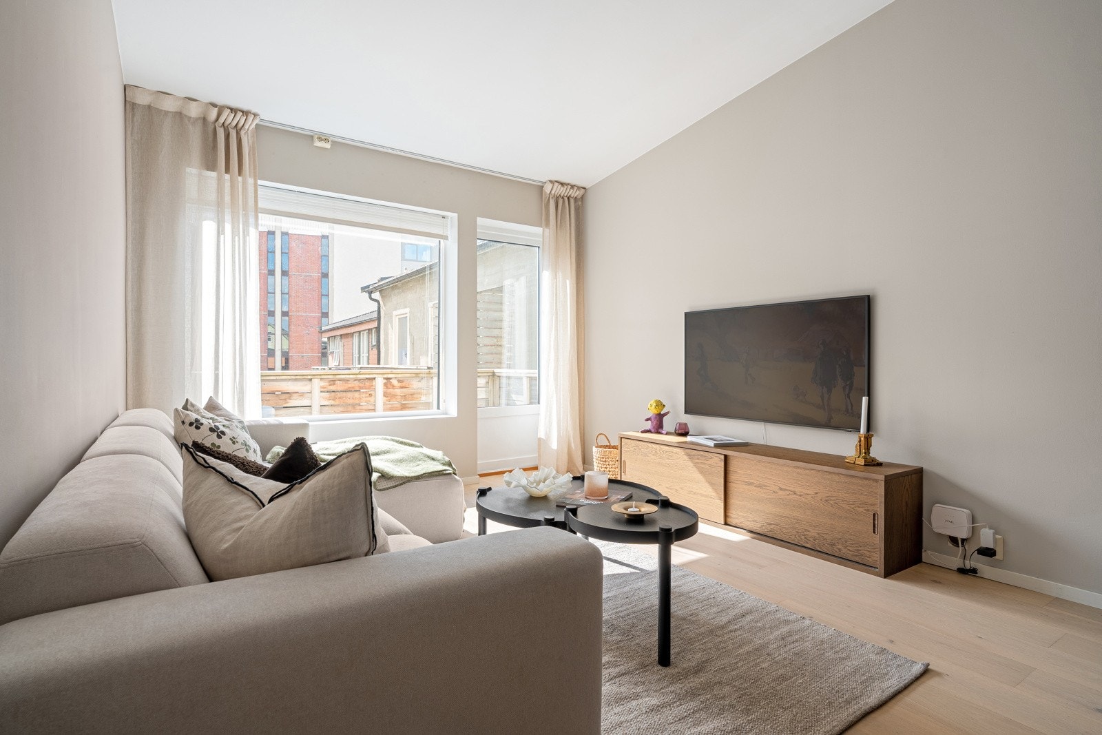 Sofagruppen har sin naturlige plass ved vinduet. Med god plass til TV på motsatt vegg. Legg merke til den generøse takhøyden og de store vindusflatene.