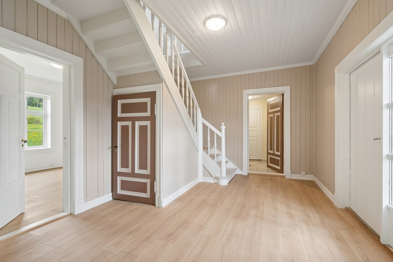 Romslig hall med malt tretrapp og klassiske fyllingsdører. Galleribilde