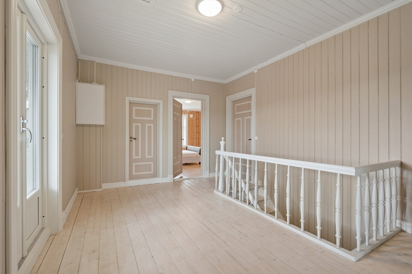 Loftsgang i andre etasje med malte tregulv og panelvegger. Galleribilde