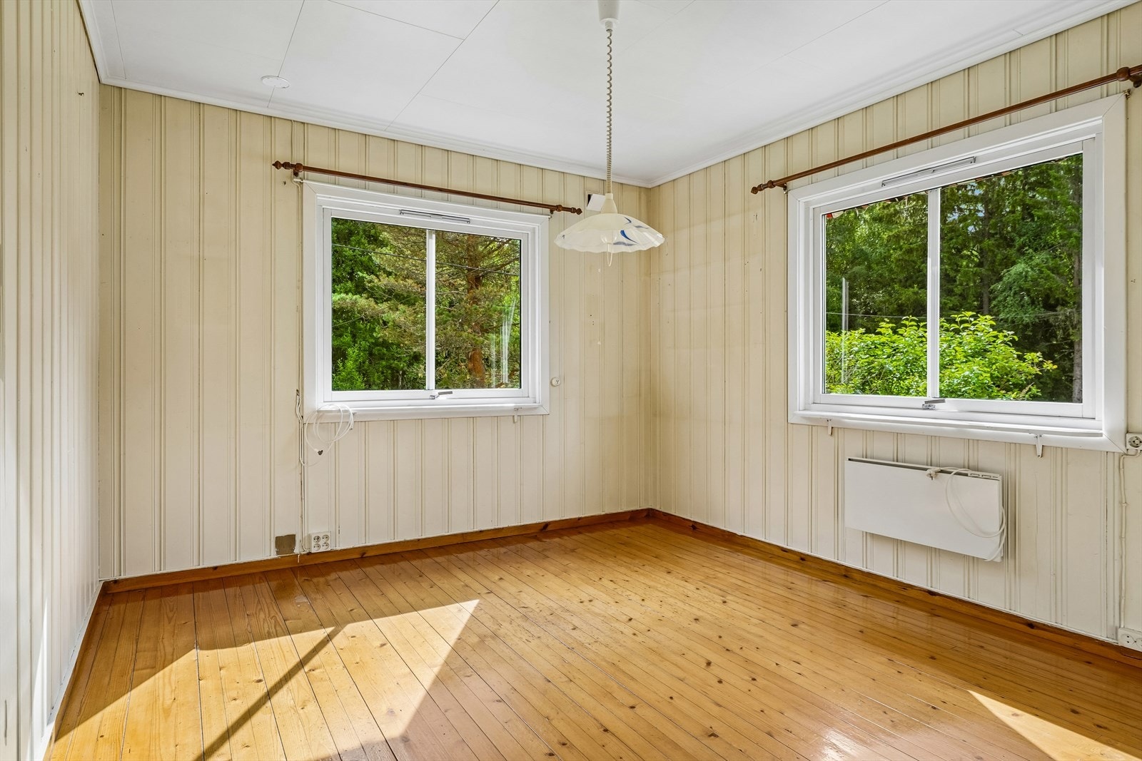 Rommet har vegger med trepanel og vinduer som vender ut mot eiendommen. Galleribilde