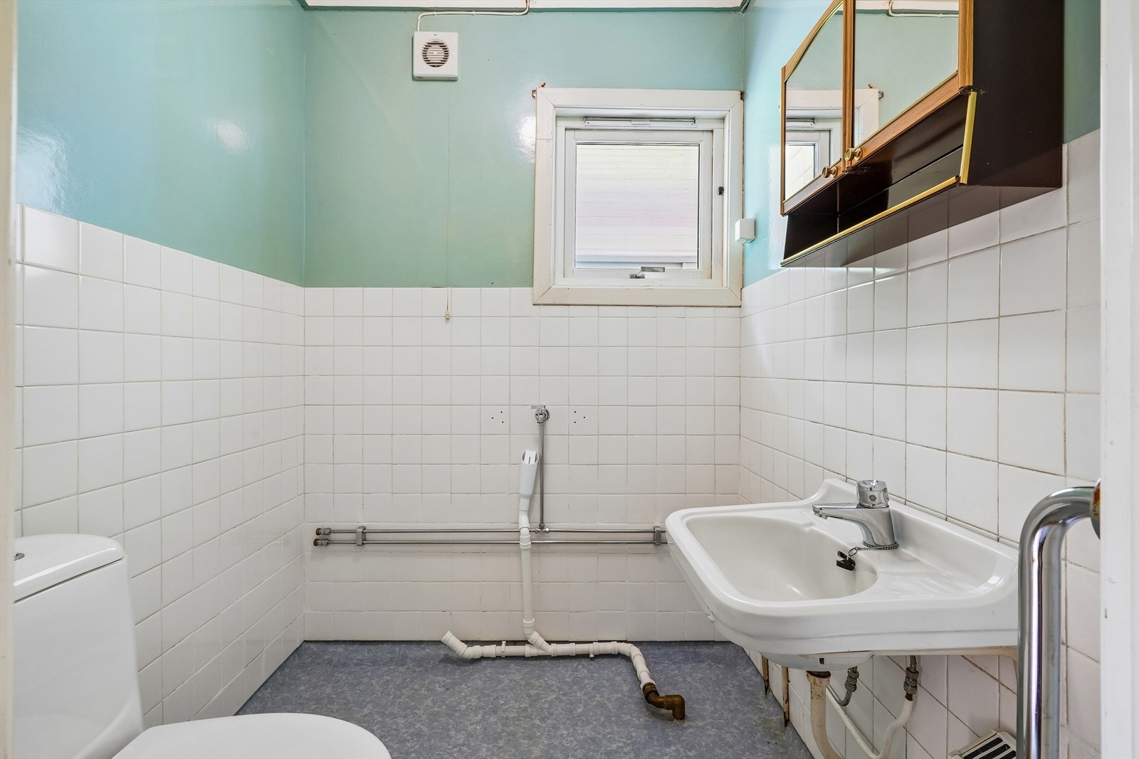 Badet er utstyrt med toalett, servant og har opplegg for vaskemaskin. Behov for renovering. Galleribilde