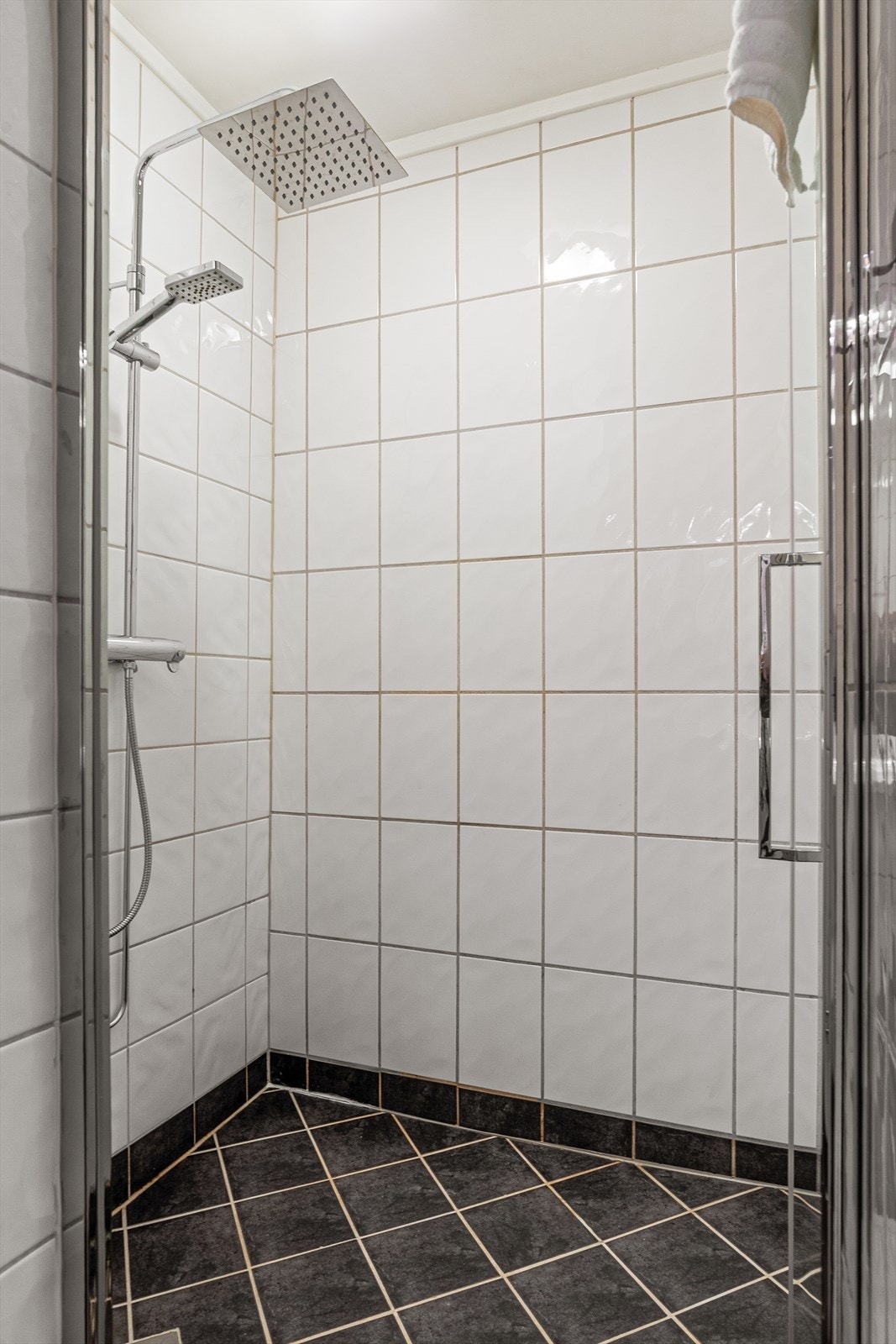 Badet er utstyrt med dusj med innfellbare glassdører, servant med baderomsinnredning med profilerte fronter og gulvstående toalett. Galleribilde