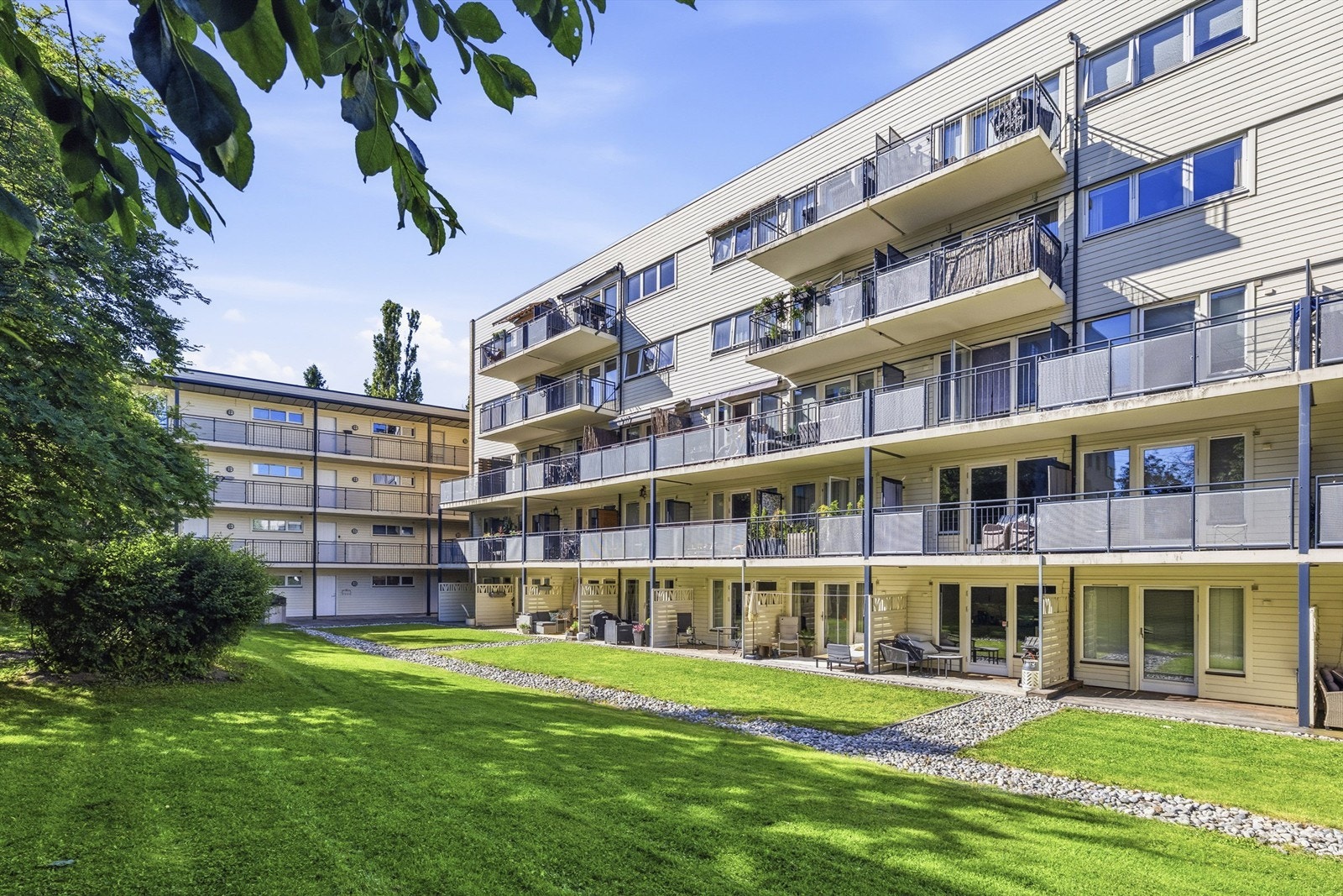 Felles tomt opparbeidet med blant annet asfalterte veier, belegningsstein, biloppstillingsplass, sittegrupper, plenarealer og andre forskjellige beplantninger Galleribilde