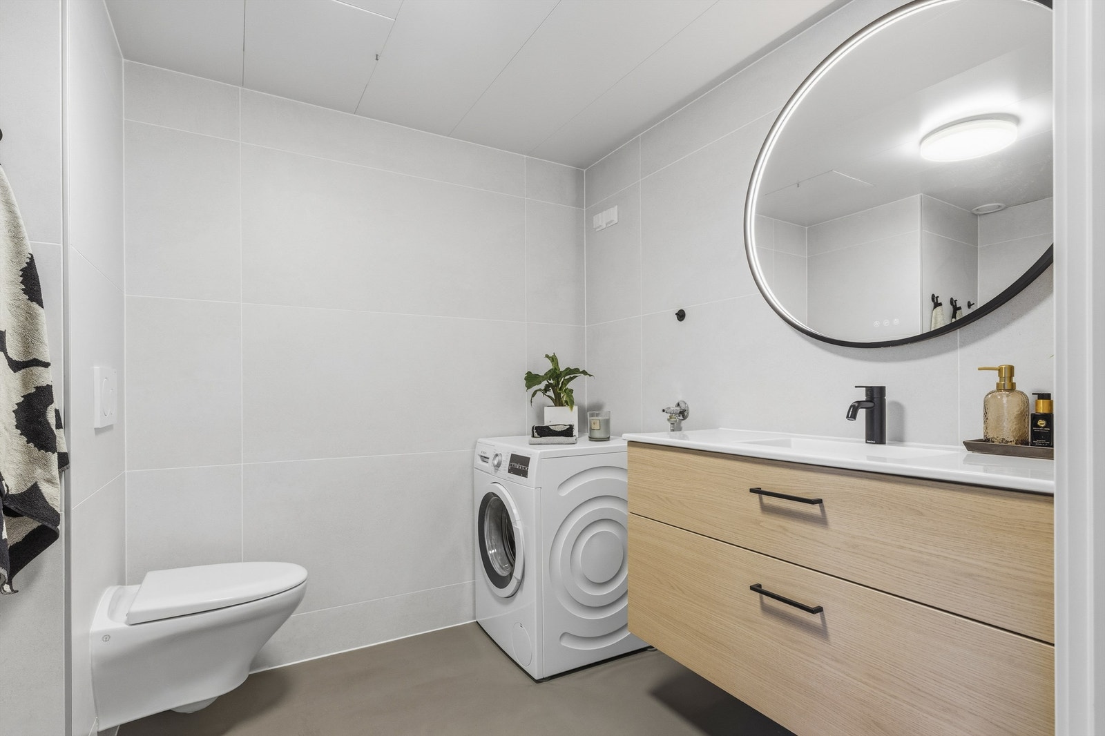 Badet består av vegghengt servantinnredning, speil med lys, dusjnisje med dører, vegghengt dusjarmatur og vegghengt toalett Galleribilde