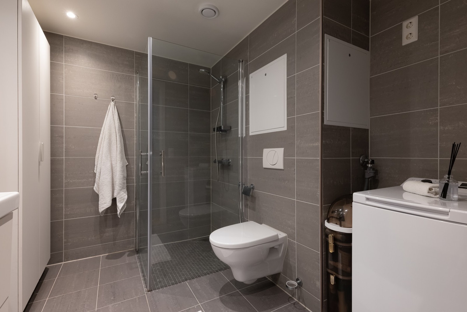 Badet har opplegg for vaskemaskin og plass til tørketrommel i praktisk nisje. Galleribilde