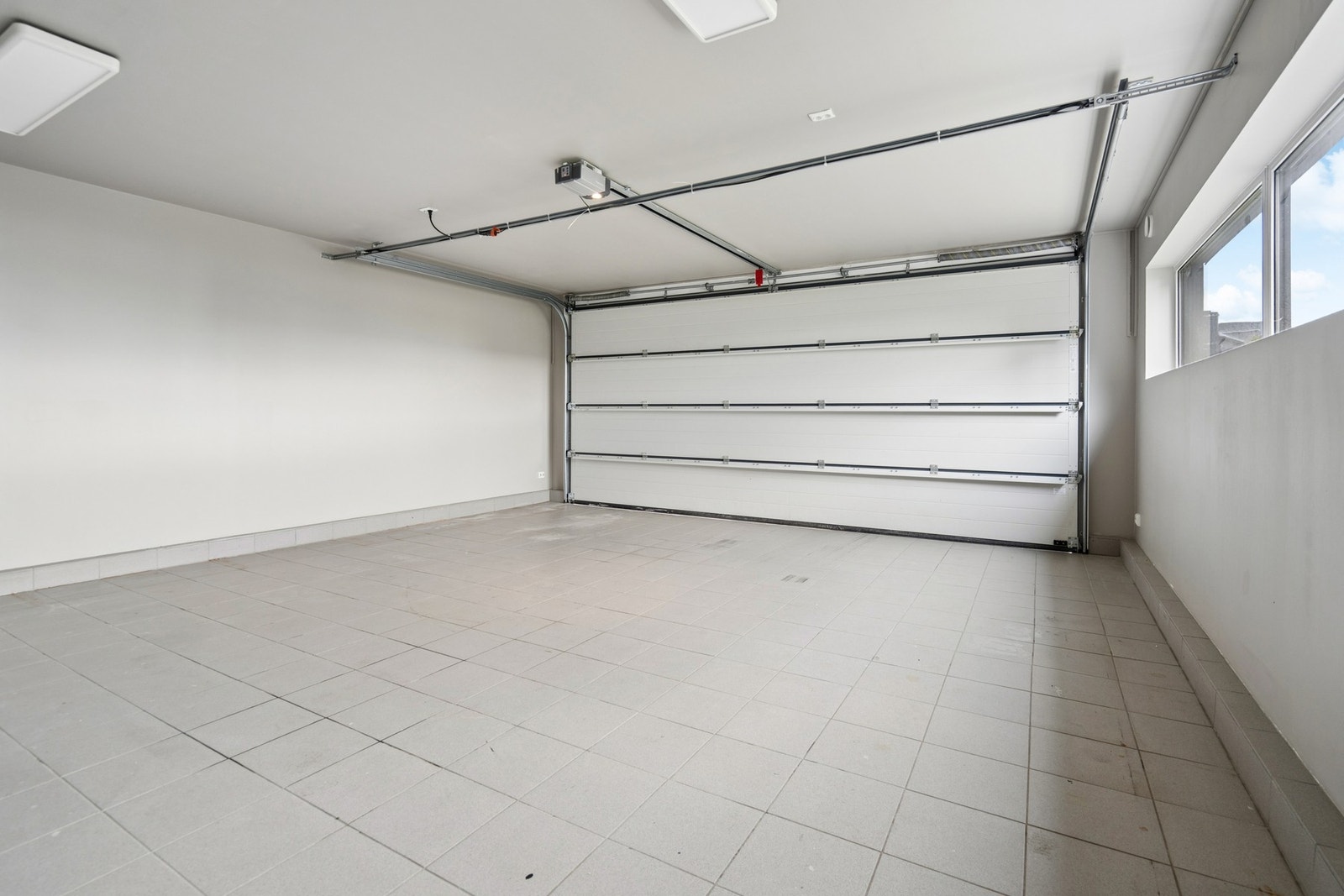 Romslig, flislagt garasje med automatisk portåpner. Galleribilde