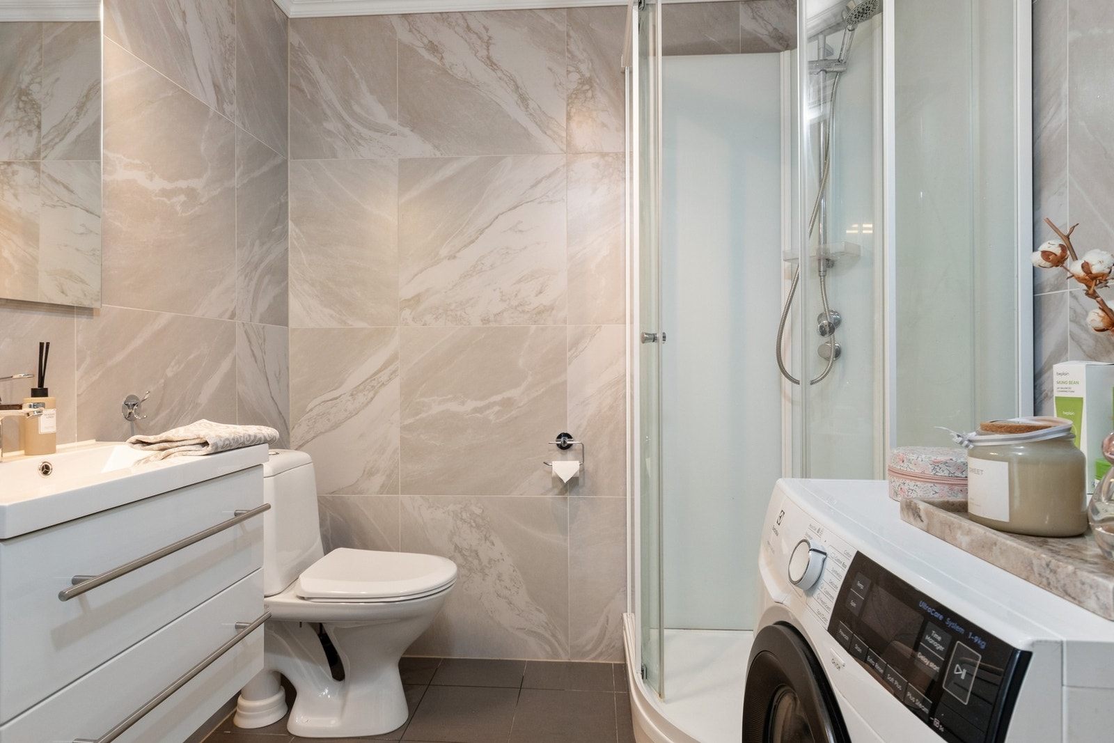 Badet ble smakfullt pusset opp i 2021 og er utført med lyse, marmorerte fliser på veggene, mørke fliser på gulvet, gulvvarme og hvitmalt himling med spotlampe. Galleribilde