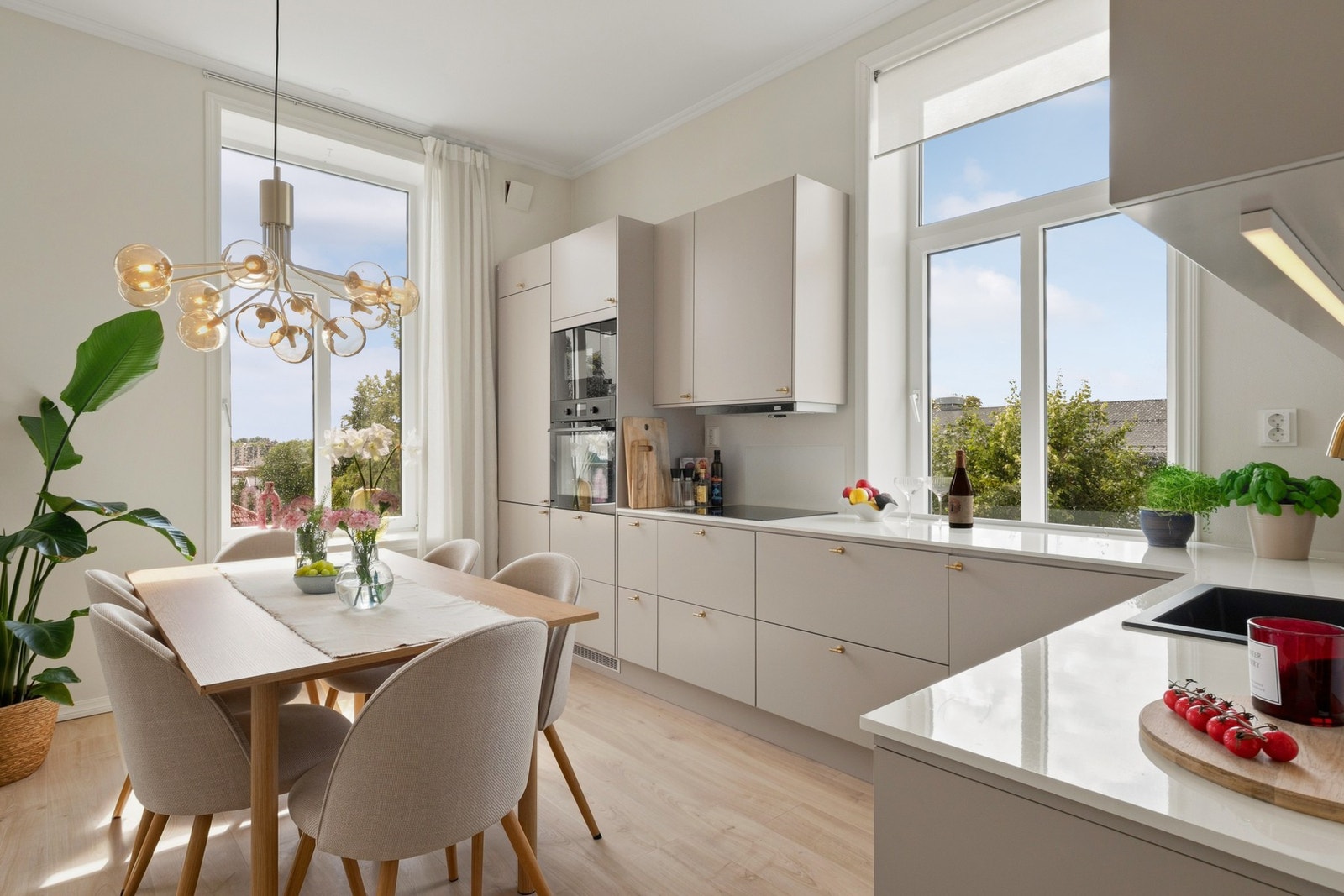 har lyse, glatte fronter med lekre messinggrep, to vitrineskap og benkeplate i tynn, lys kompositt med vaskekum i sort kompositt og messingkran. Galleribilde