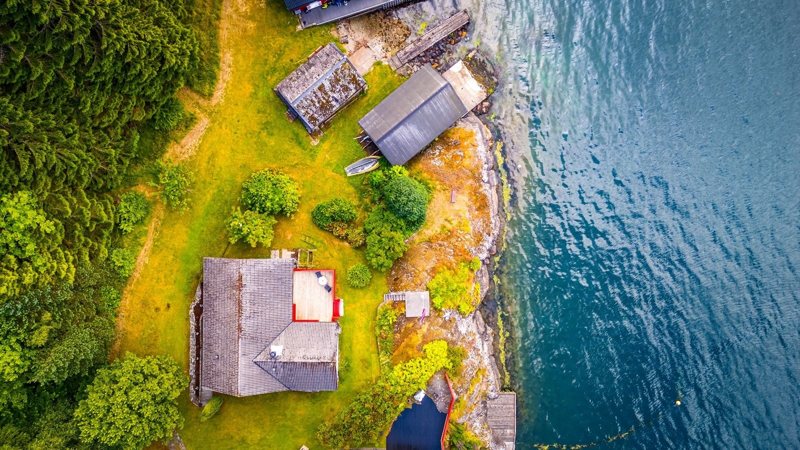 Flyfoto som viser eiendommens unike plassering helt i vannkanten. Galleribilde