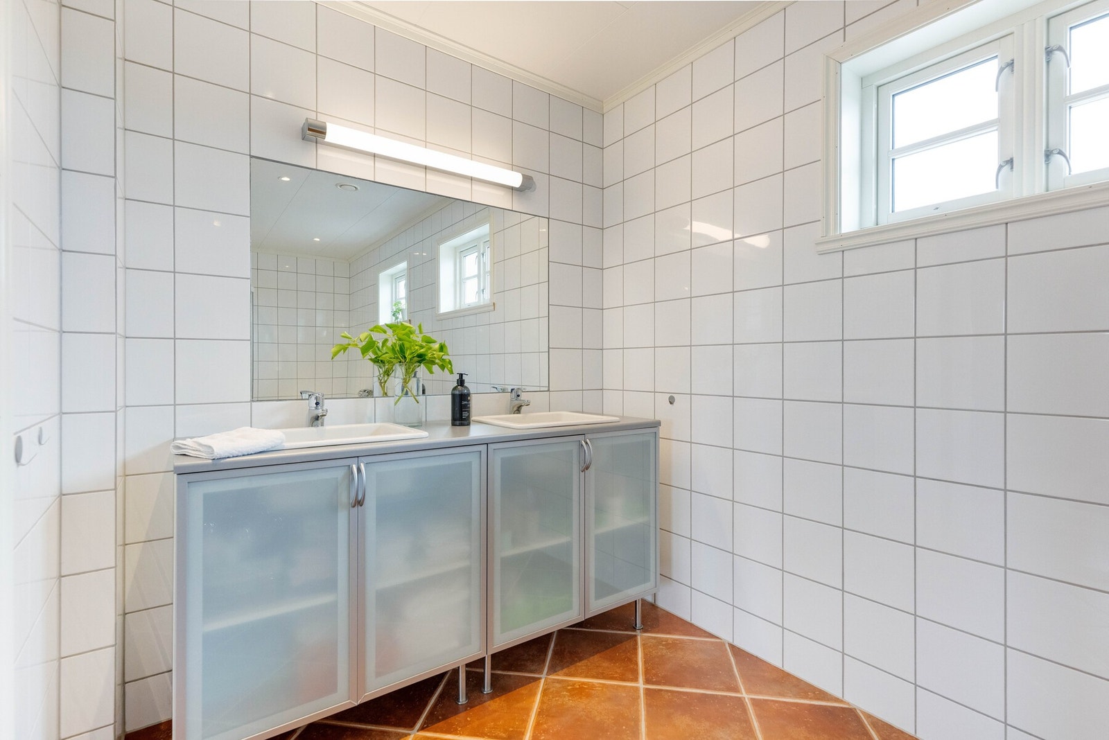 Det er innredet med opplegg for badekar, vegghengt toalett, dusjhjørne med glassdører og dobbel servant med innredning, speil og belysning. Galleribilde