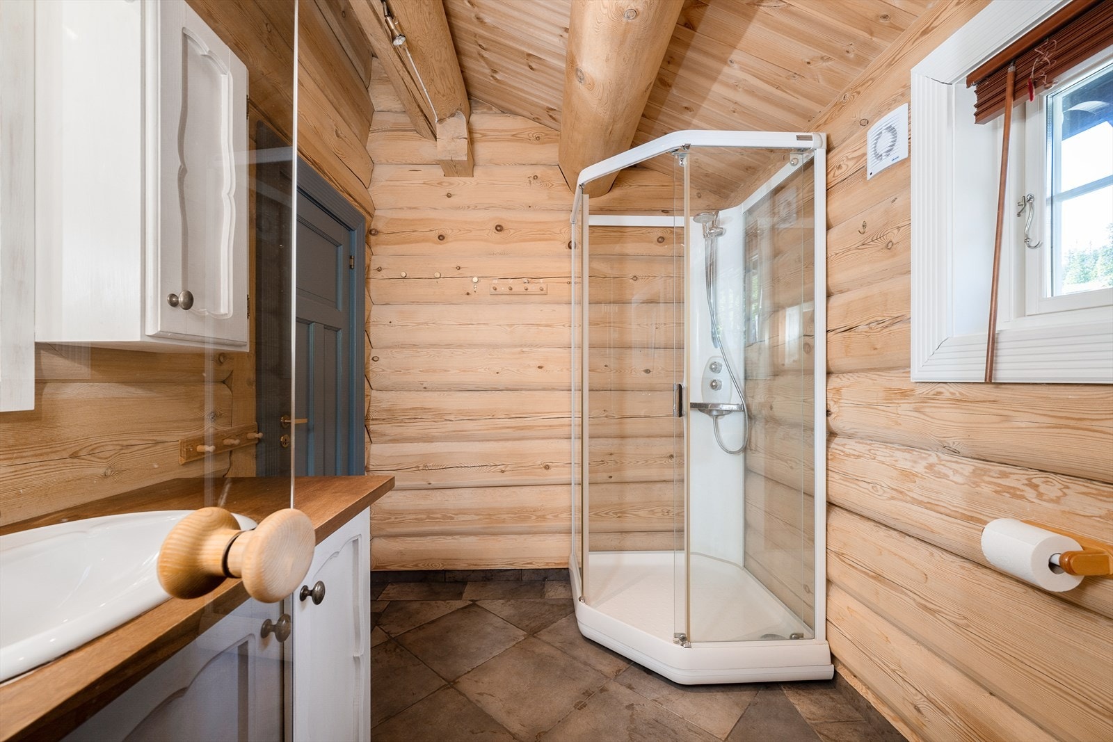 Badet har dusjkabinett og trepanel på veggene. Galleribilde