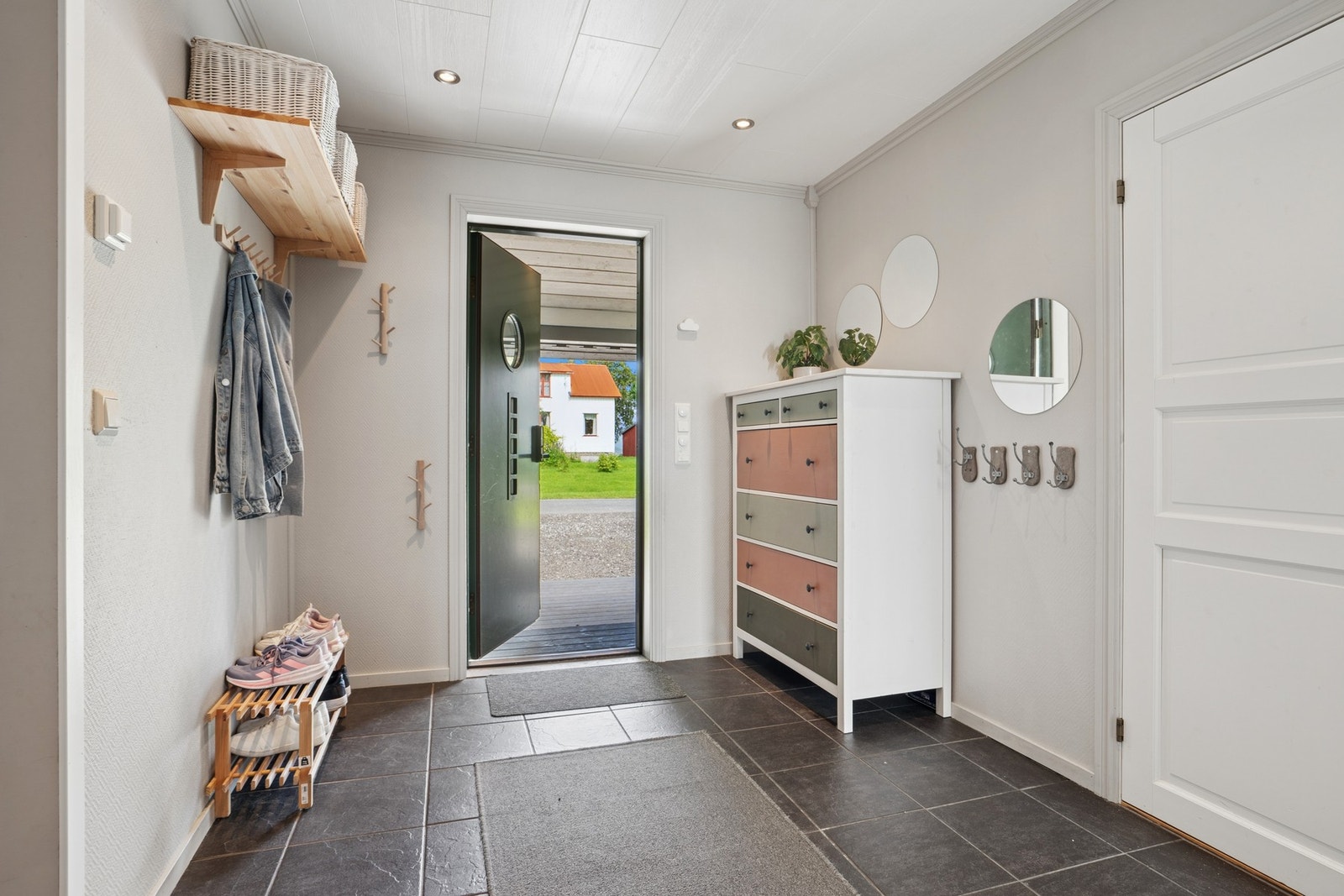 Ve3lkommen inn til en entré med flislagt gulv og plass til oppbevaring av yttertøy Galleribilde