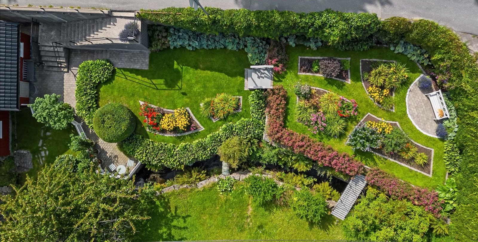 Oversikt over den velstelte hagen med gjennomtenkte bed og beplantning. Galleribilde