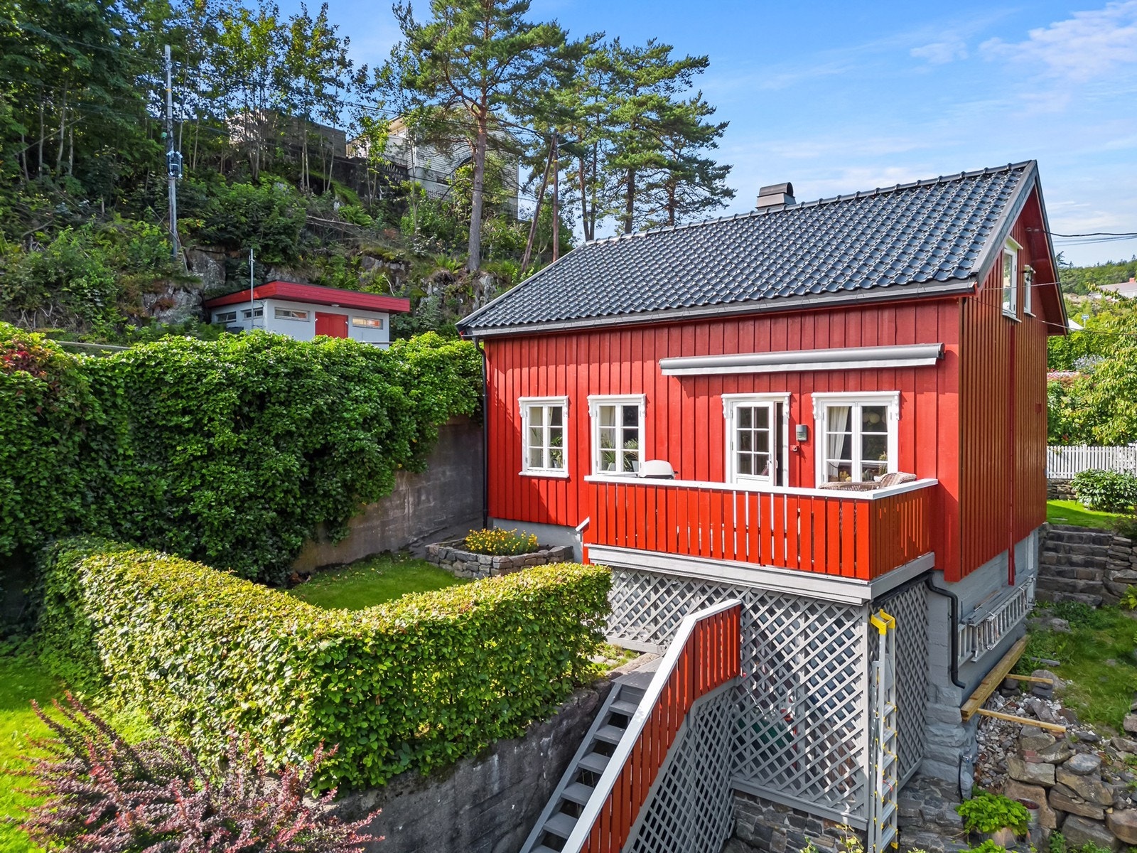 Tomten har opparbeidede terrengforhold med beplantning og steinmurer. Galleribilde