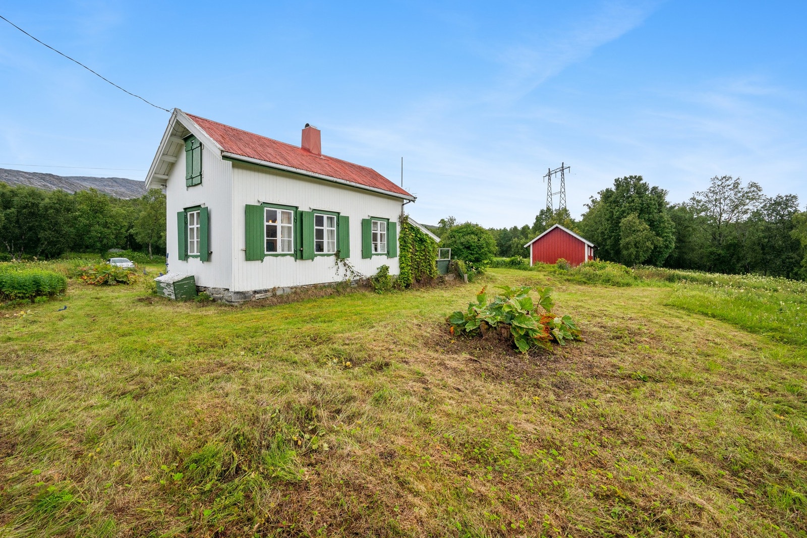 Eneboligen/fritidsboligen har en tradisjonell stil med hvitmalt panel og grønne skodder. Galleribilde