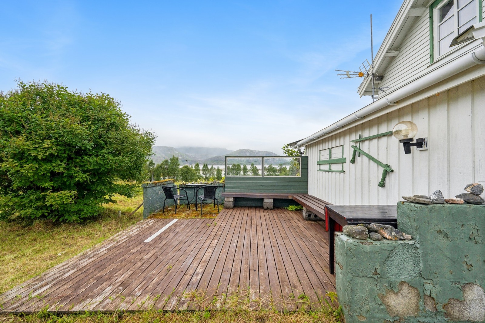 Romslig terrasse med plassbygde benker og utsikt mot sjøen. Galleribilde