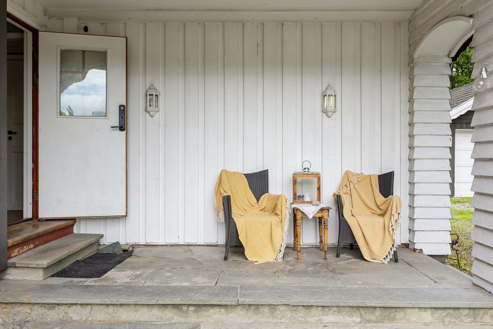 Overbygd inngangsparti med plass til en liten sittegruppe. Galleribilde