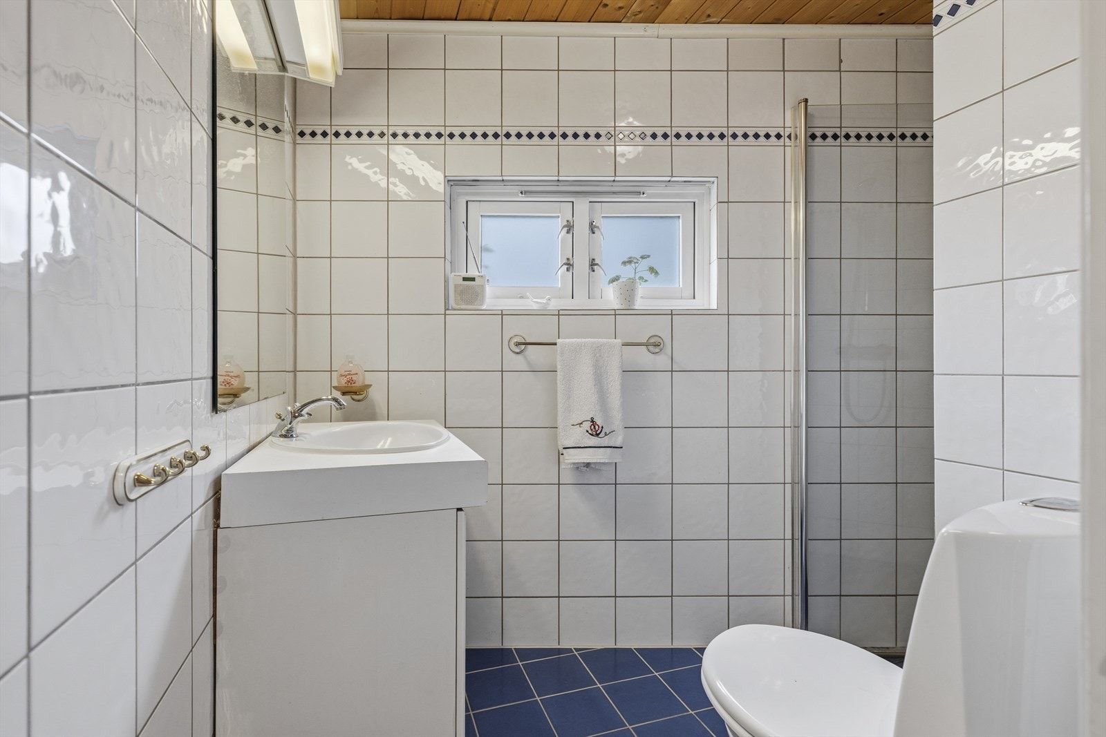 Flislagt baderom fra 1992. Badet er innredet med toalett, dusj og servant med underskap Galleribilde
