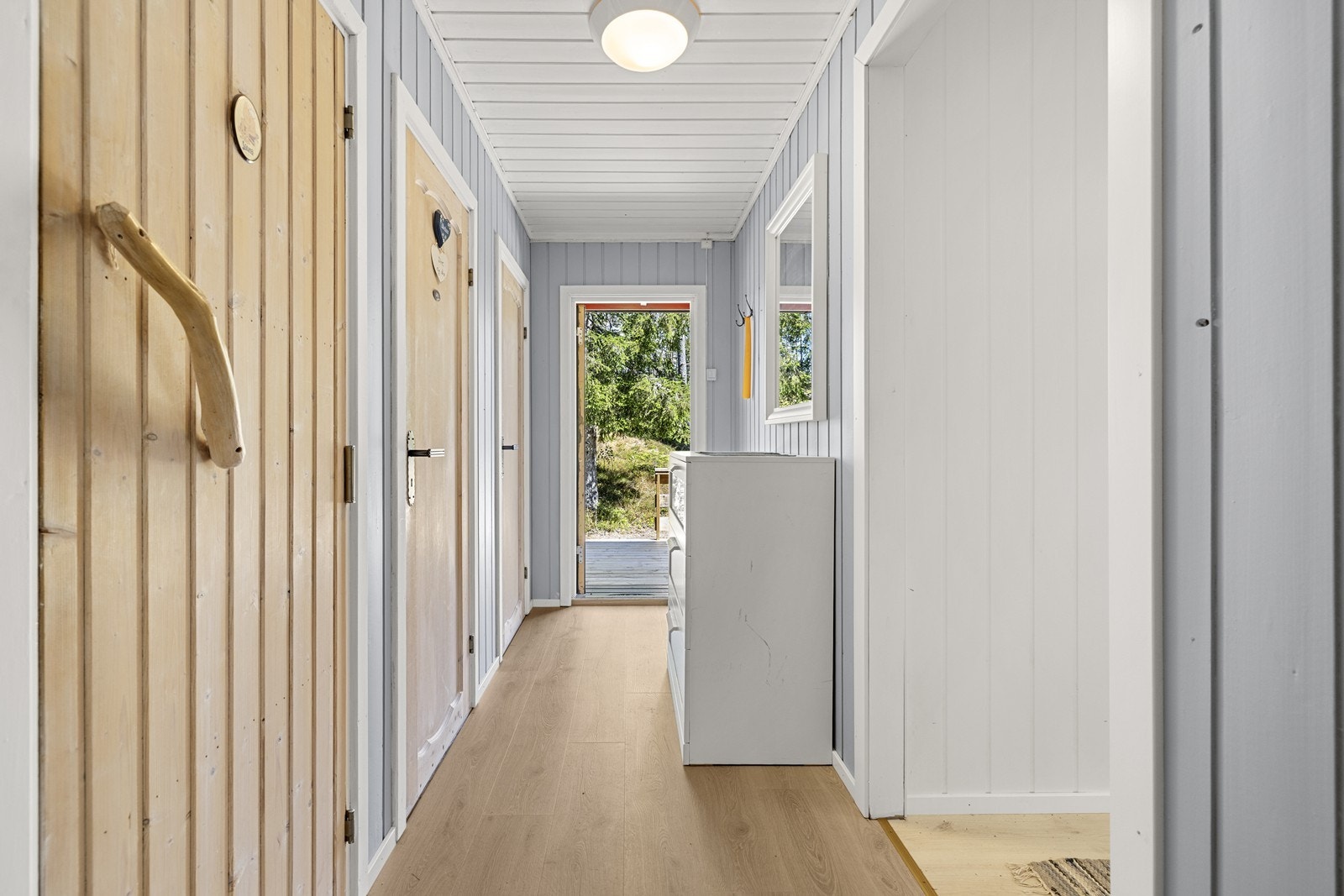 Velkommen inn til en langstrakt entré med plass til oppbevaring av sko og yttertøy, og gangen fungerer som et naturlig bindeledd mellom oppholdsrommene, soverommene og våtrommene. Galleribilde