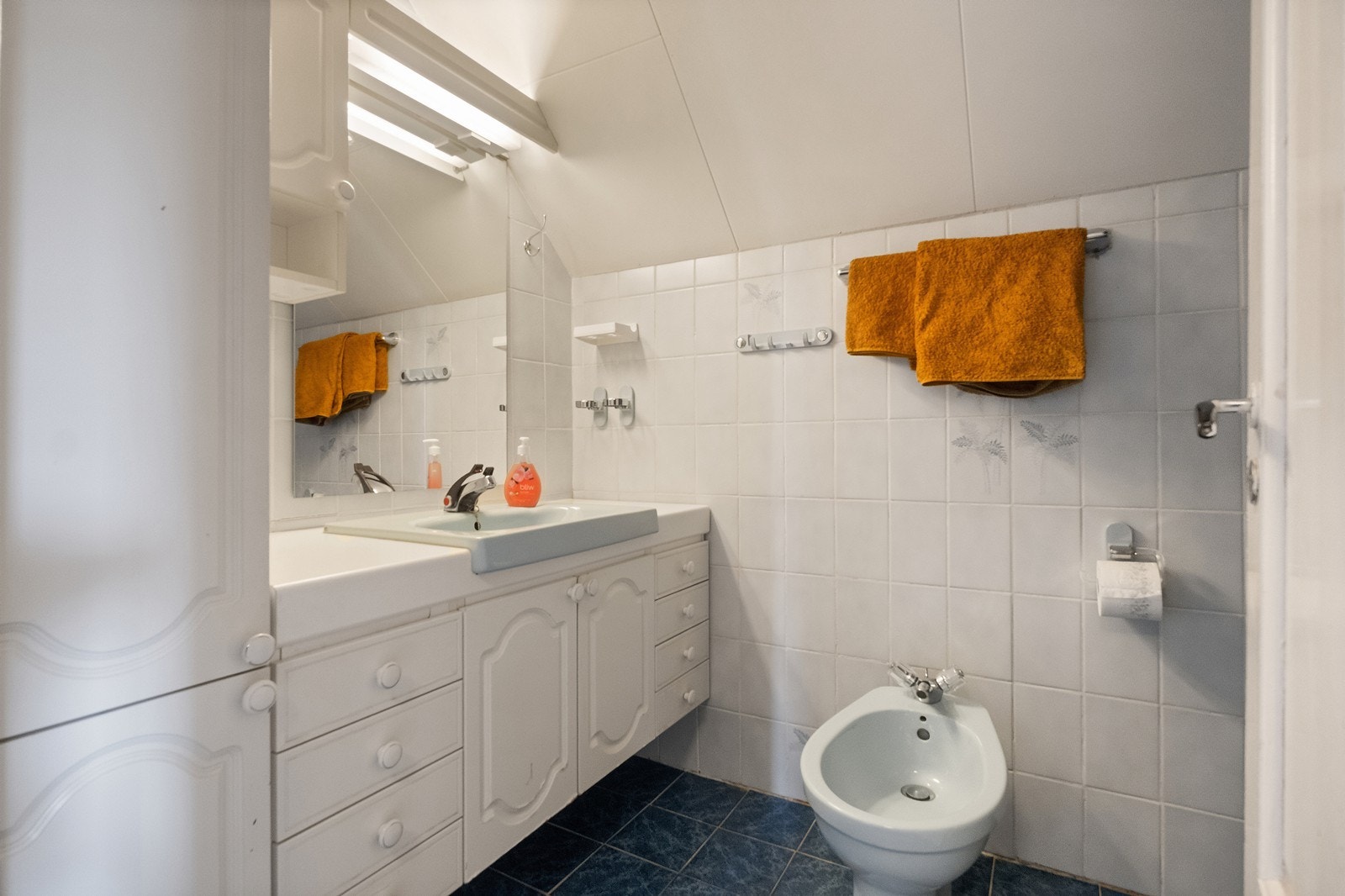 Flislagt bad utstyrt med en romslig baderomsinnredning og bidet. Galleribilde