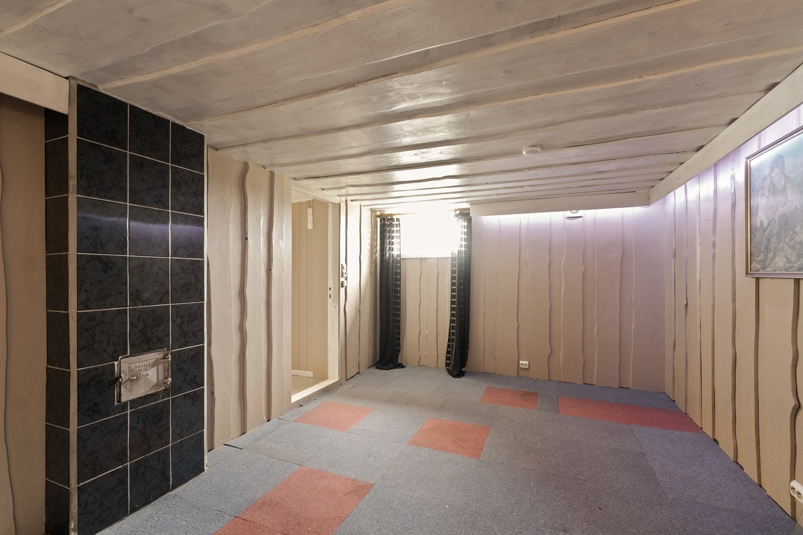 Kjellerrom innredet med panel på vegger og teppebelagte gulv. Galleribilde