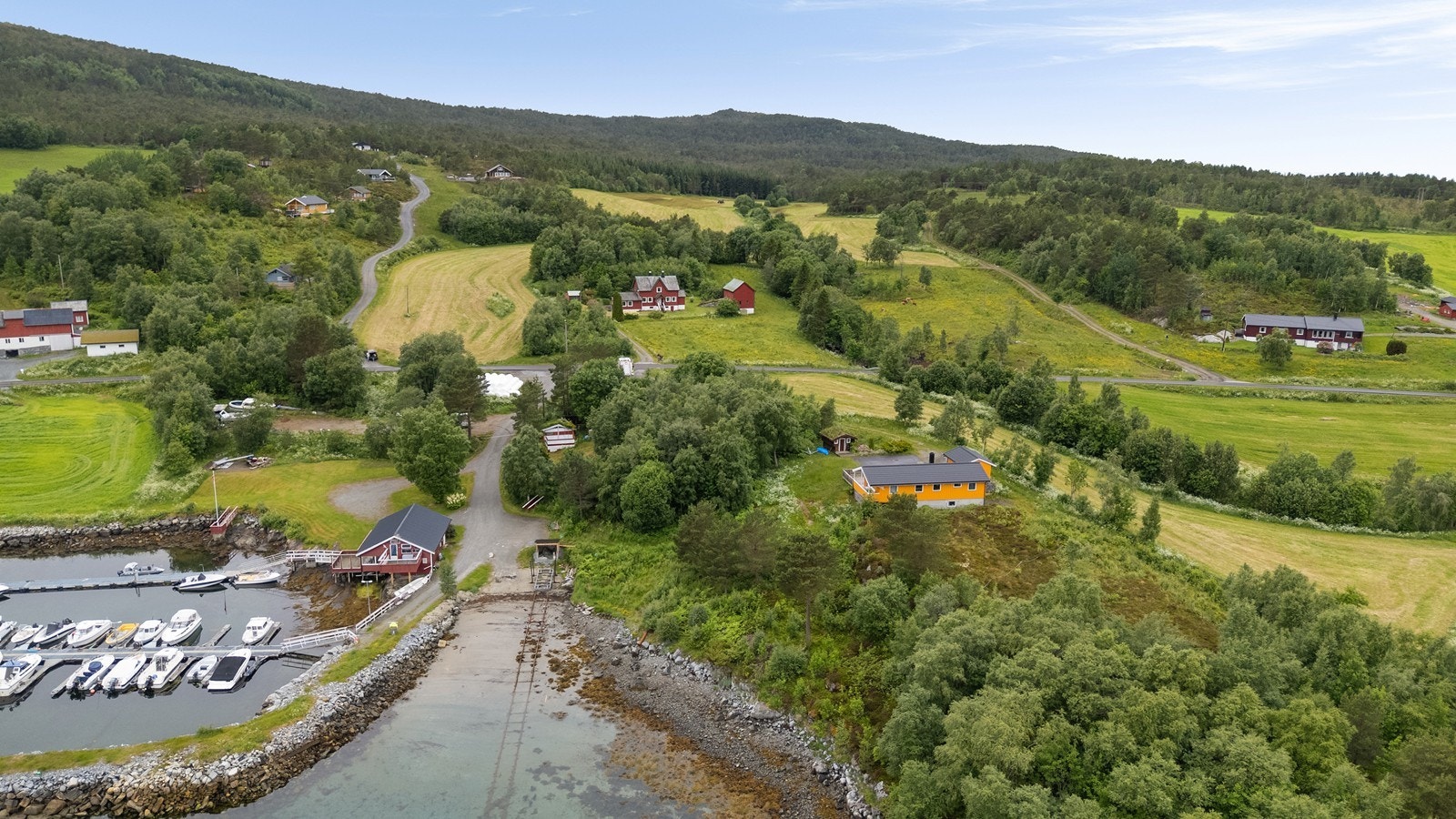 Dronebilde av eiendommen og nærliggende omgivelser viser nærheten til sjøen. Galleribilde