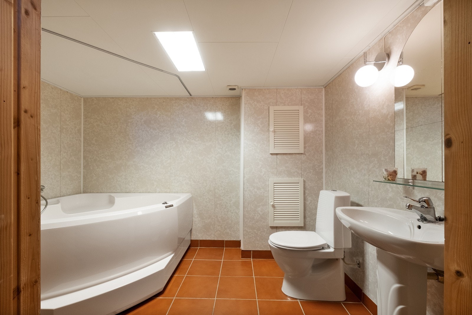 Badet i kjelleren har flislagt gulv, baderomsplater og panel på veggene, og er utstyrt med hjørnebadekar, toalett og frittstående servant. Galleribilde
