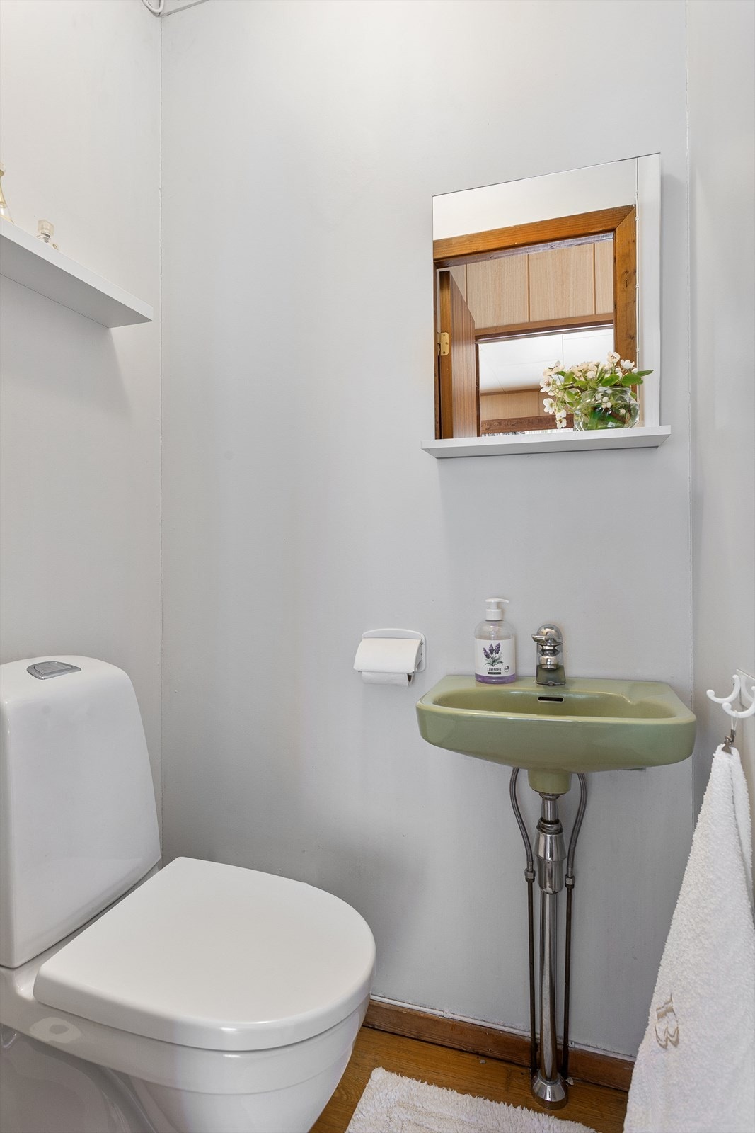 Toalettrom med parkett på gulv. Innredet med vegghengt servant og gulvstående toalett. Galleribilde